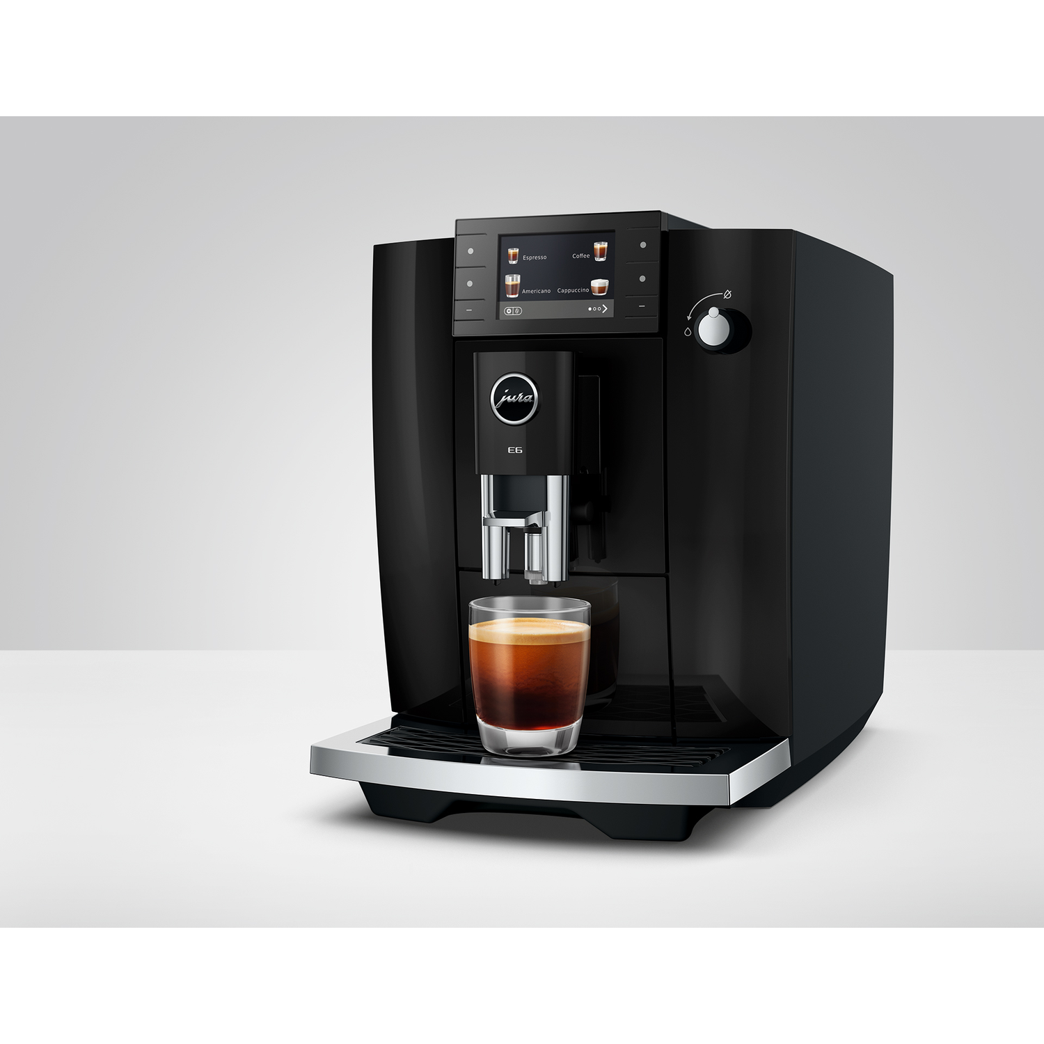 Zwarte koffiemachine met espressoglas op lekbak.