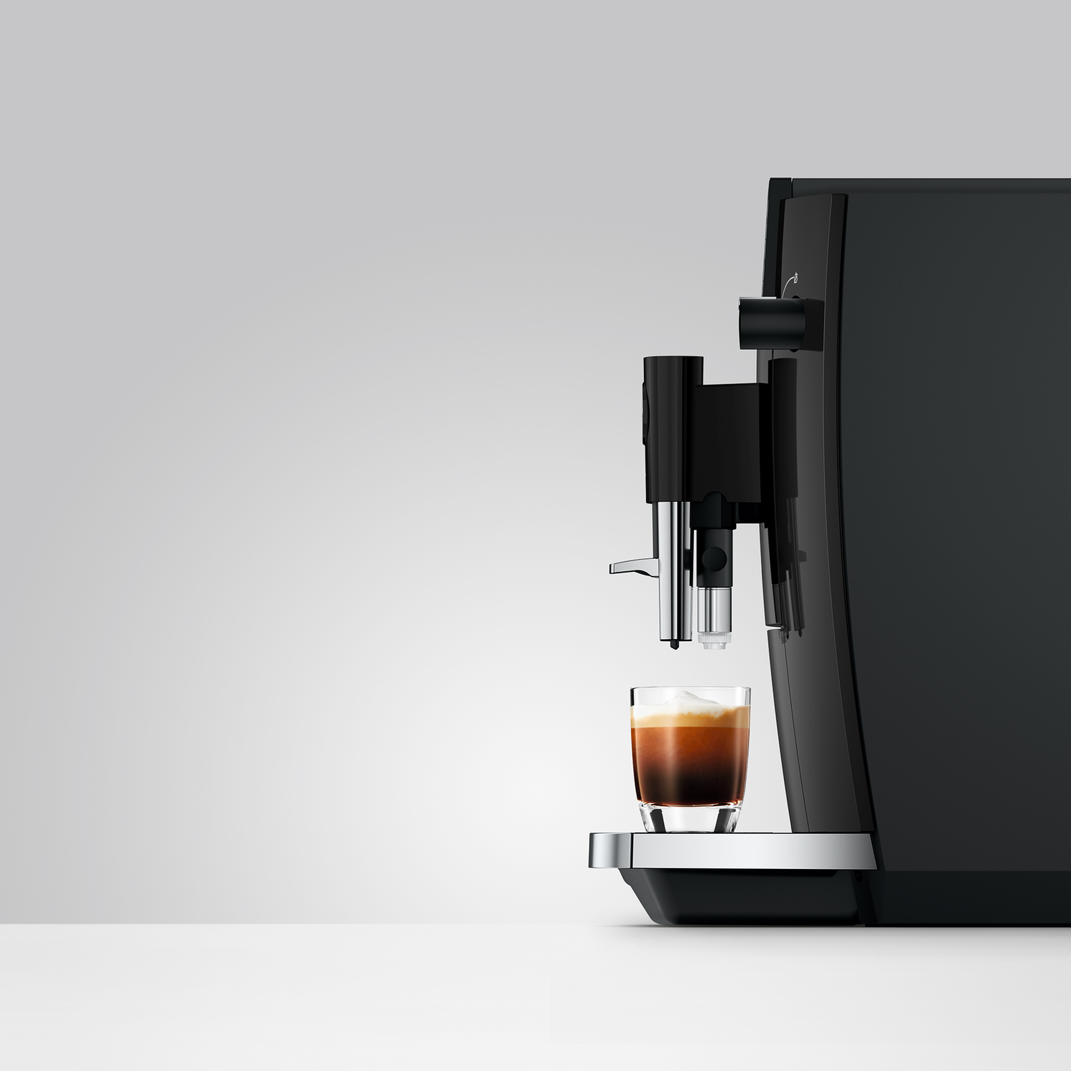 Zwarte koffiemachine schenkt espresso in een glas op een witte tafel.