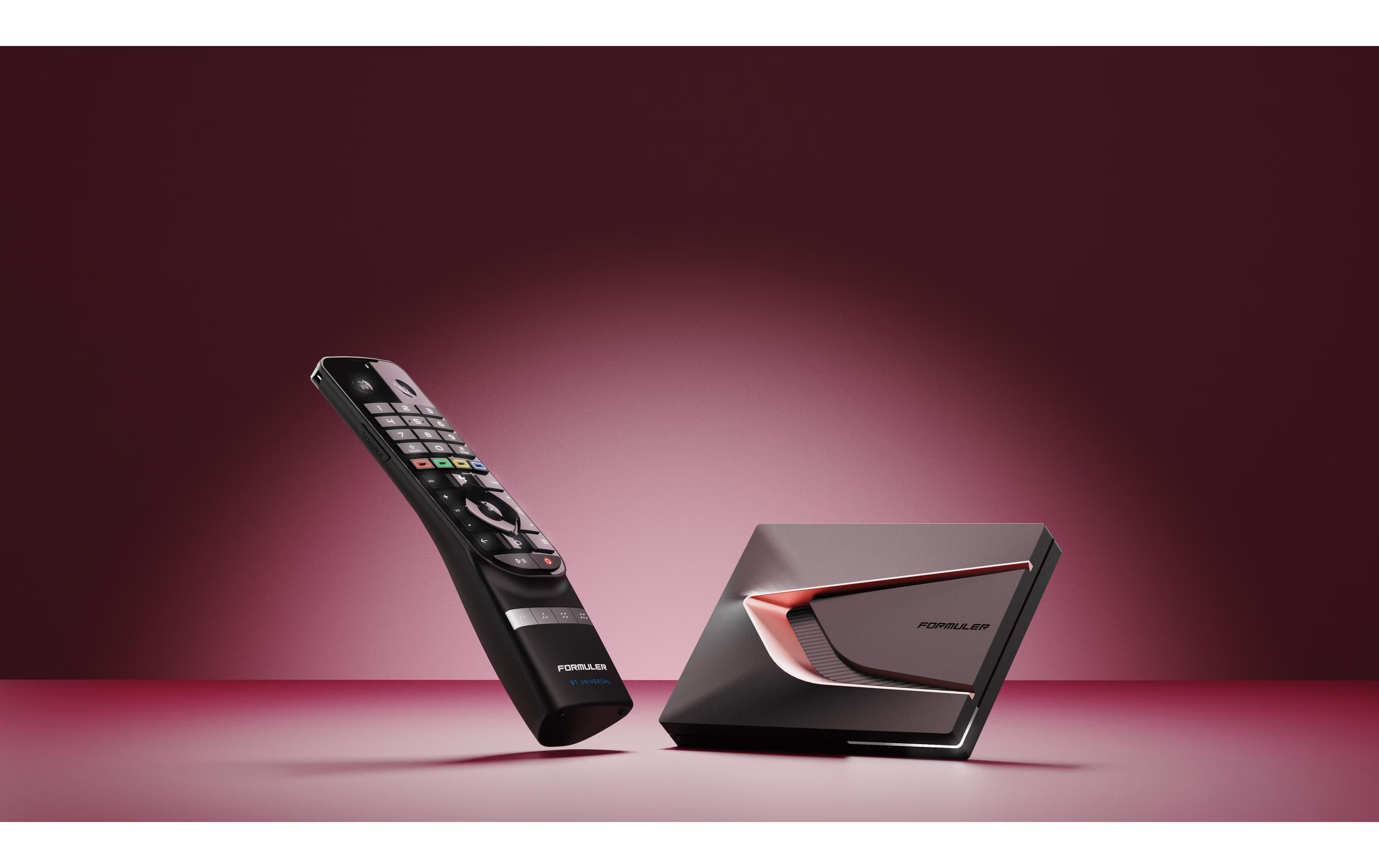 Une télécommande noire et un décodeur sur fond rouge.