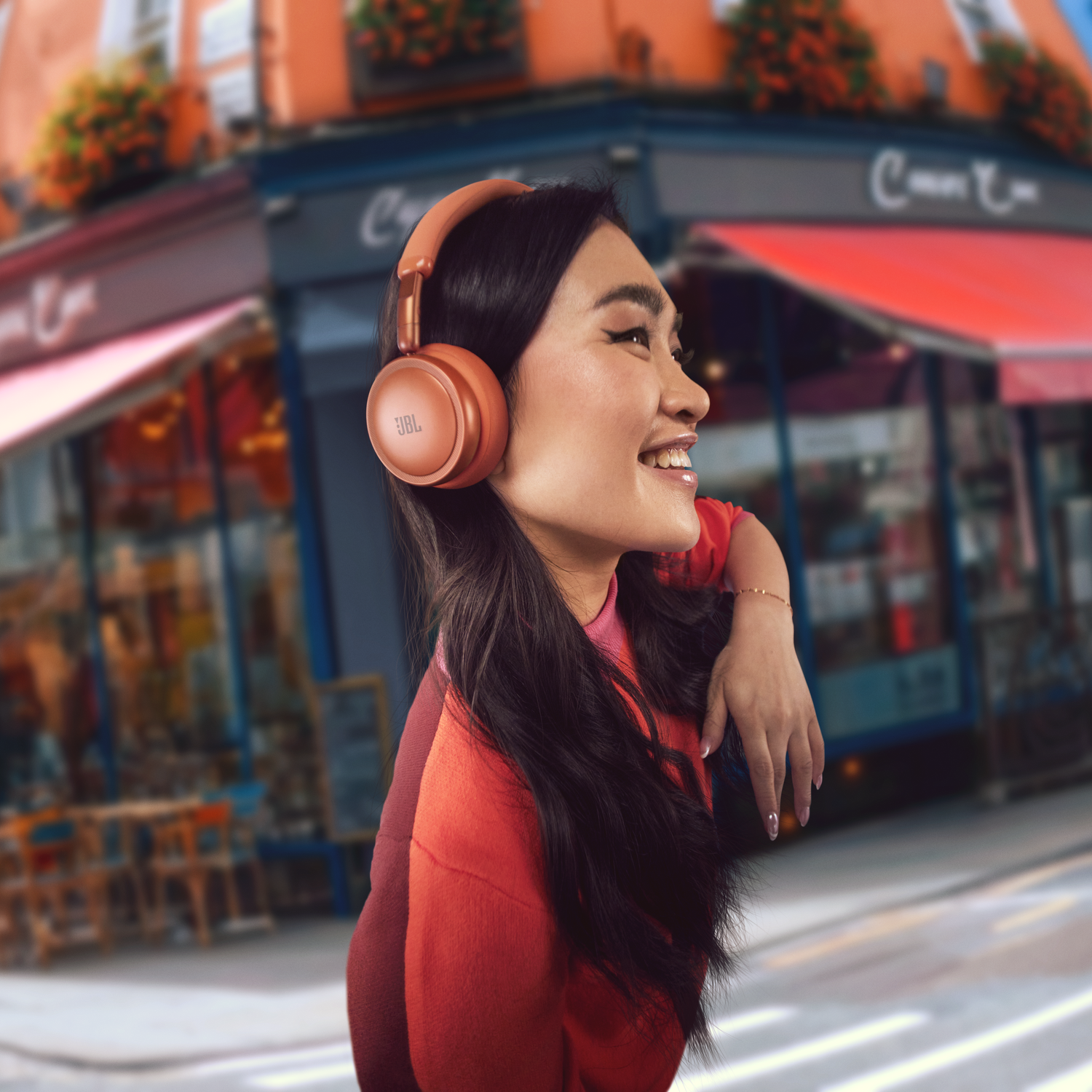 A woman wearing headphones on a busy street background.