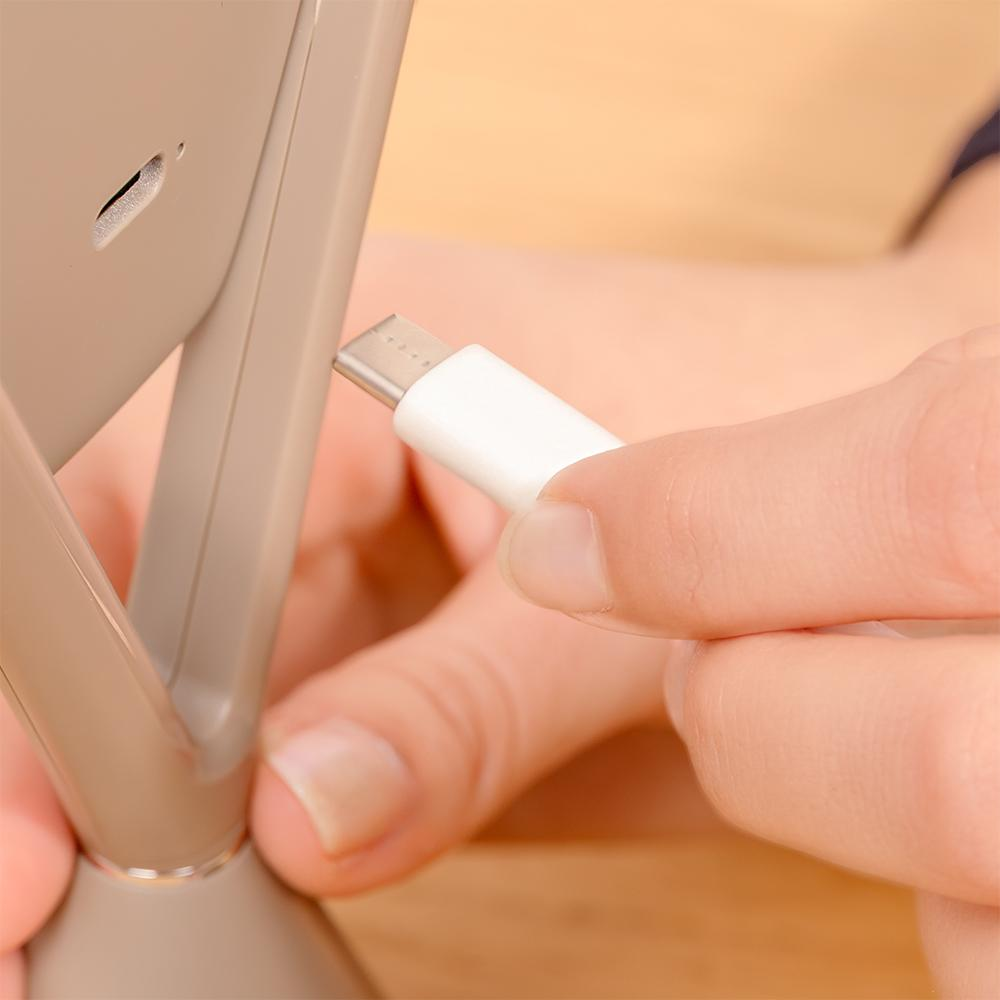 La punta de un cable USB-C blanco se está enchufando en un dispositivo gris.