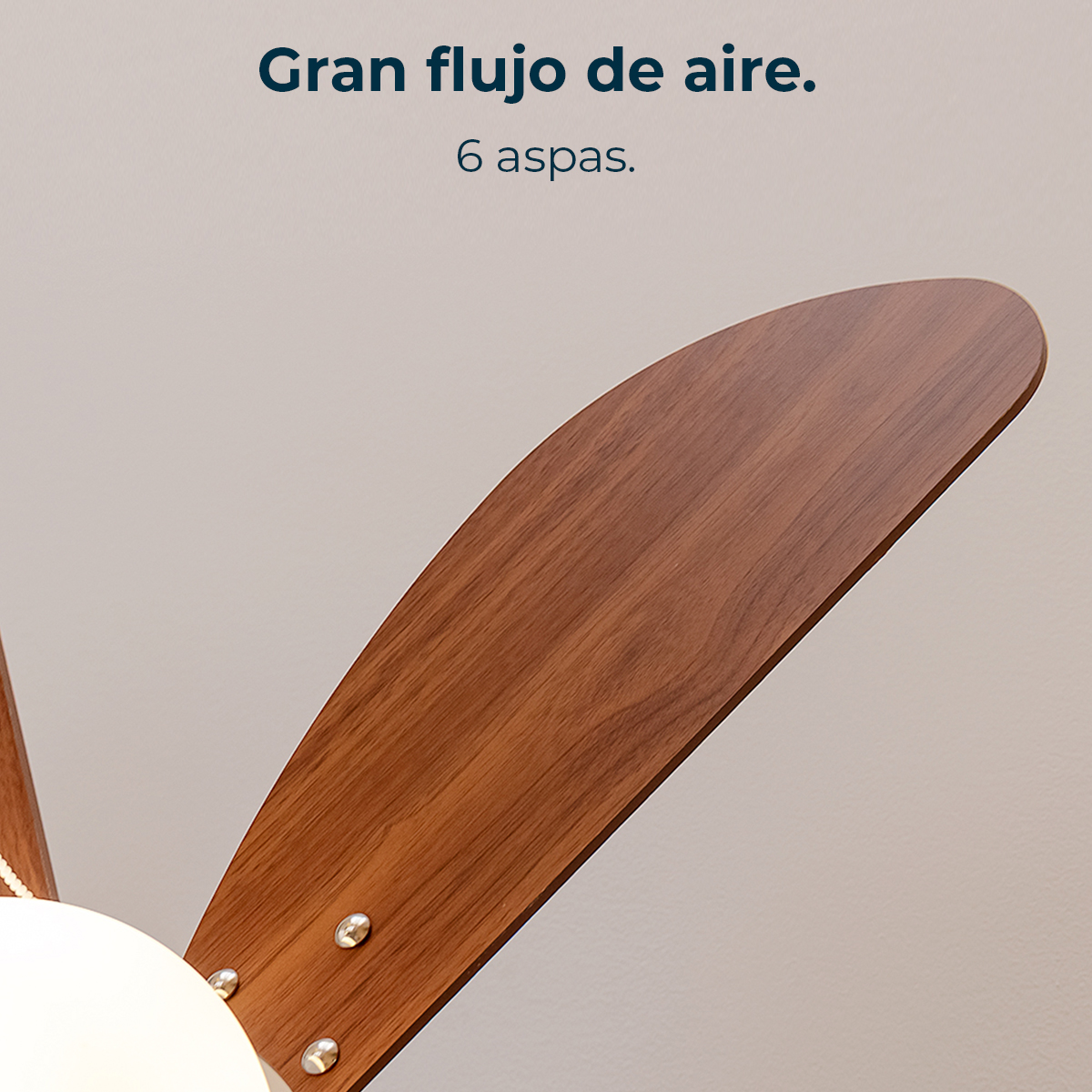 Primer plano de una pala de ventilador de madera con remaches metálicos y parte de una luz.