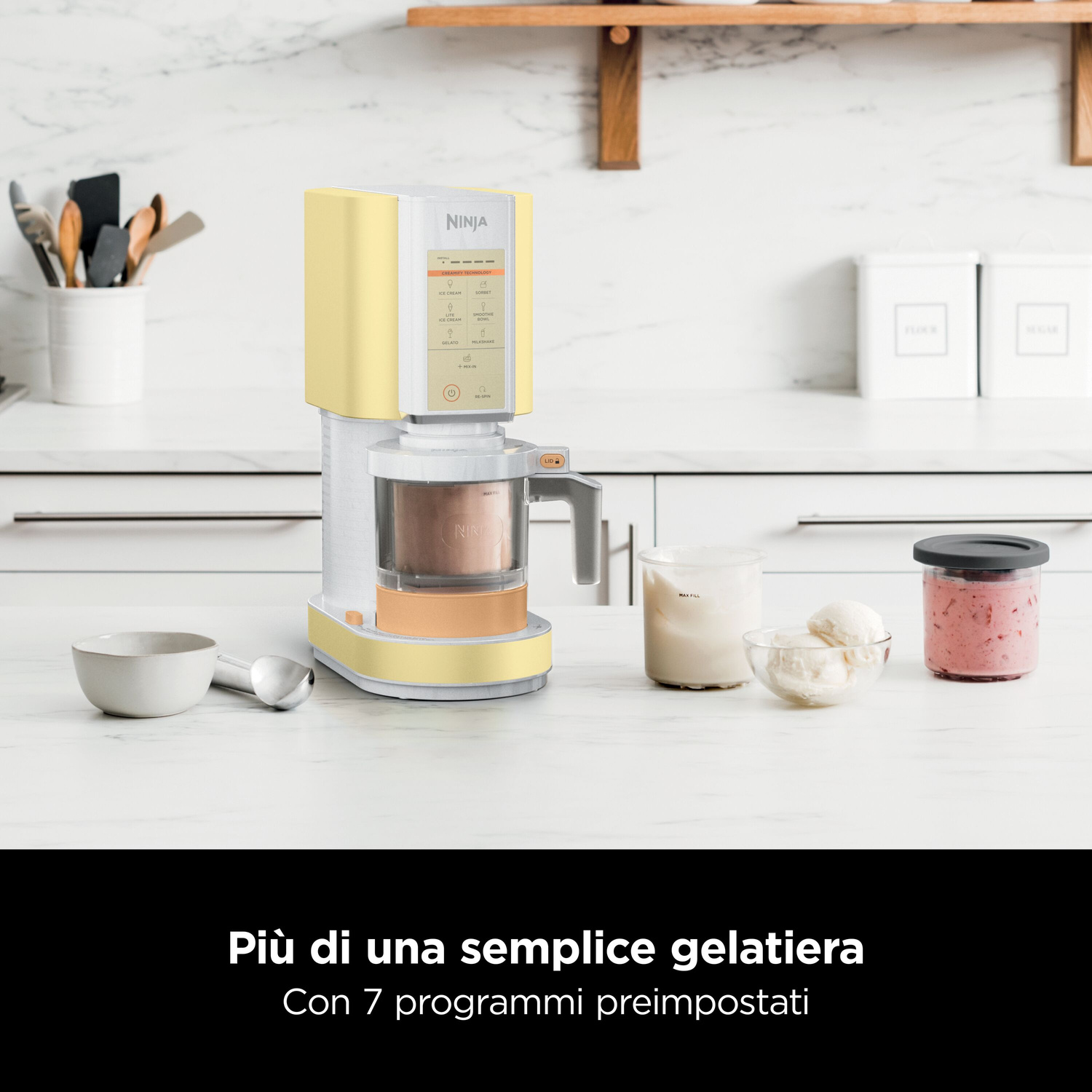 Una gelatiera Ninja gialla su un bancone da cucina accanto a gelato e mix di frutti di bosco.