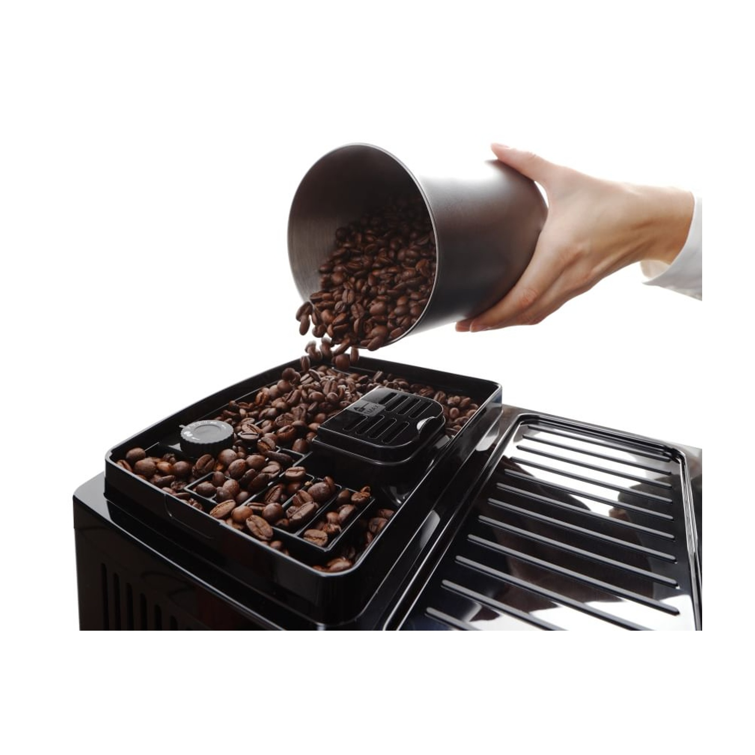 Una mano versa chicchi di caffè da un contenitore in una tramoggia per macchine da caffè.