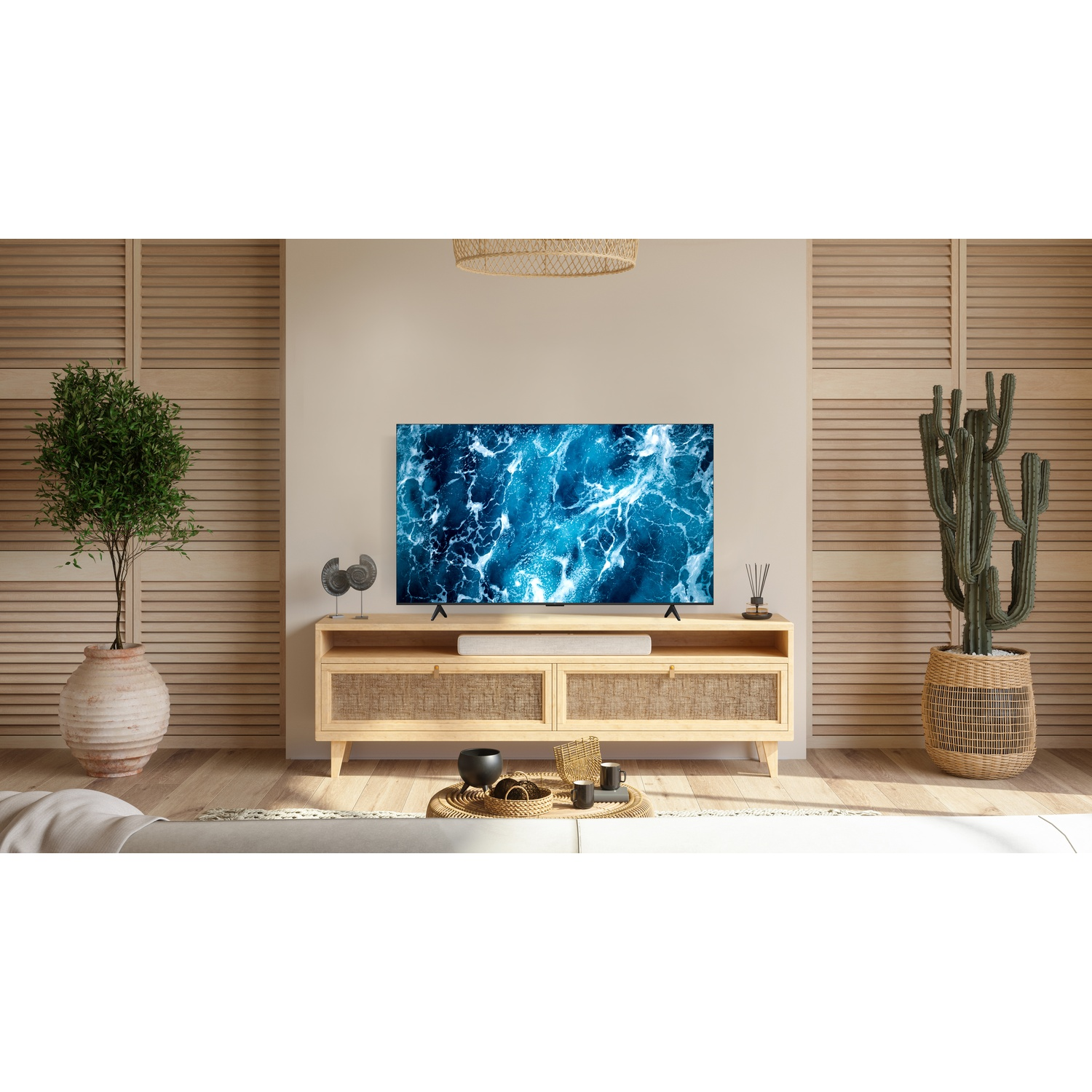 Un televisore mostra un'immagine blu dell'oceano su un mobile in legno con piante.