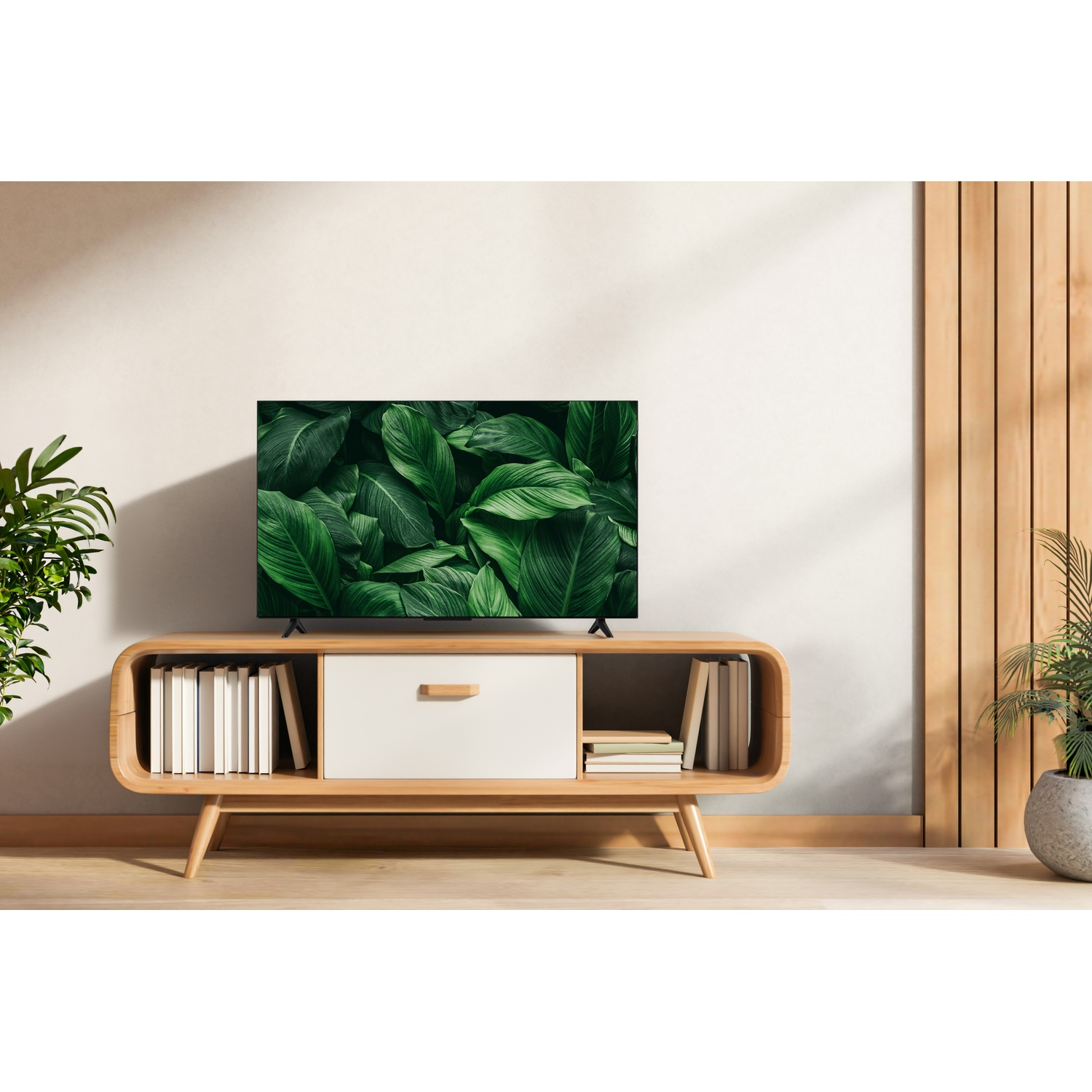 Una TV moderna su un mobile in legno mostra foglie verdi. Libri e una pianta completano la scena.
