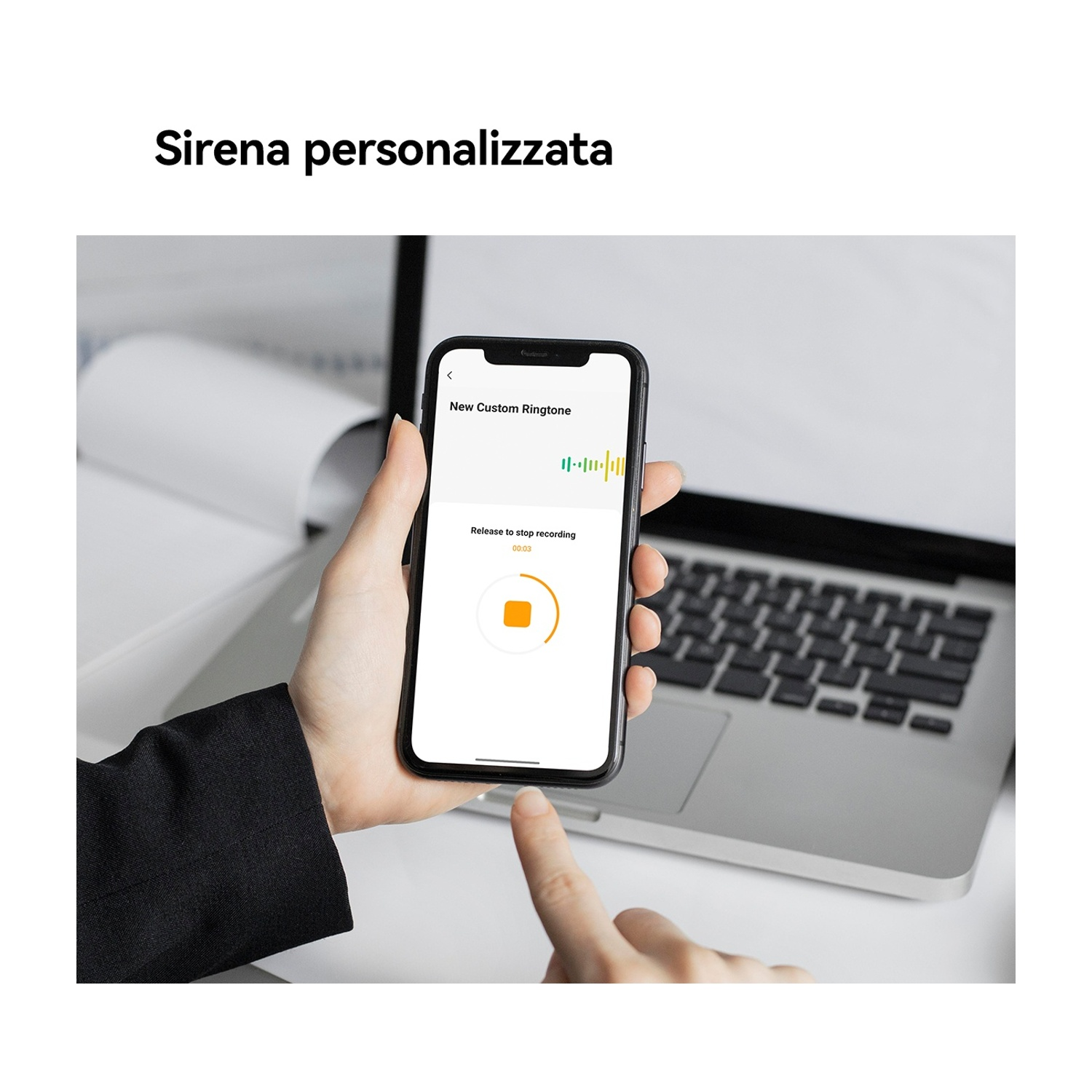 Una mano tiene uno smartphone con un'app di registrazione. Un laptop è sullo sfondo.