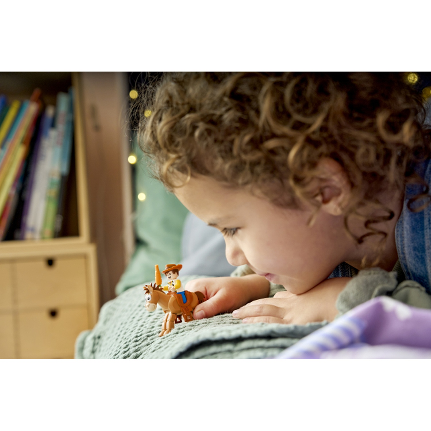 Un bambino guarda un cowboy giocattolo su un cavallo. Libreria sullo sfondo.