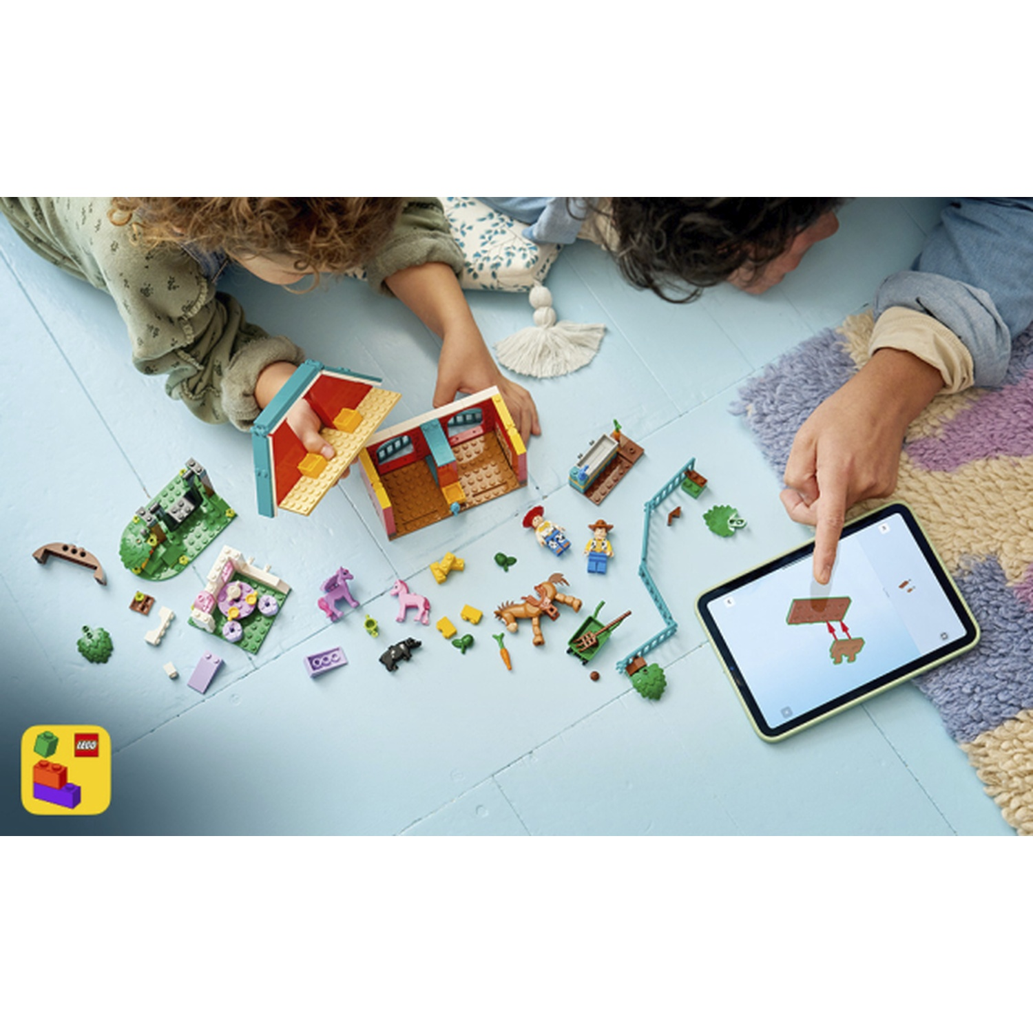 Bambini costruiscono con LEGO sul pavimento, usando un tablet come guida.
