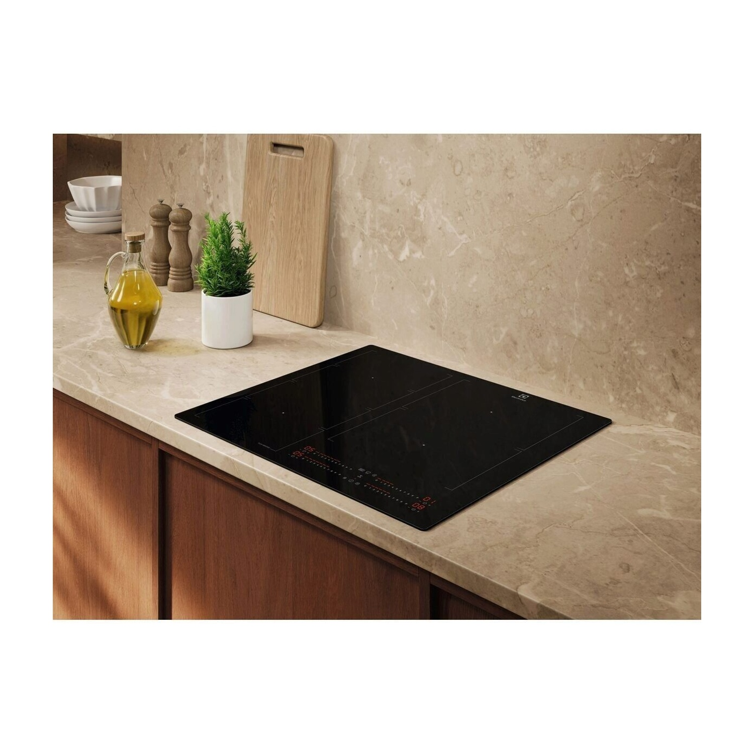Un piano cottura a induzione nero su un piano di lavoro in marmo con utensili da cucina.