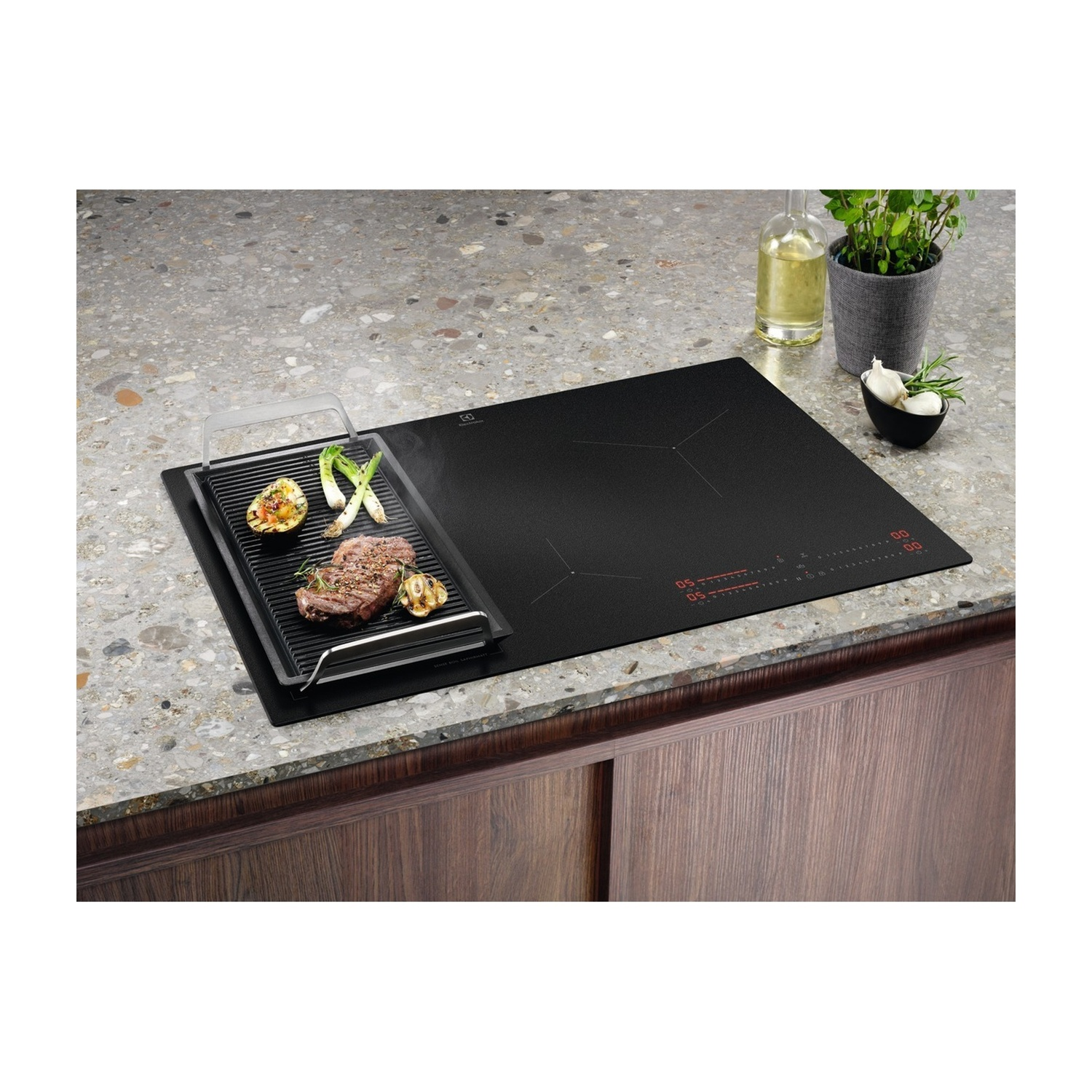 Un piano cottura a induzione con piastra grill, bistecca, verdure e aglio.