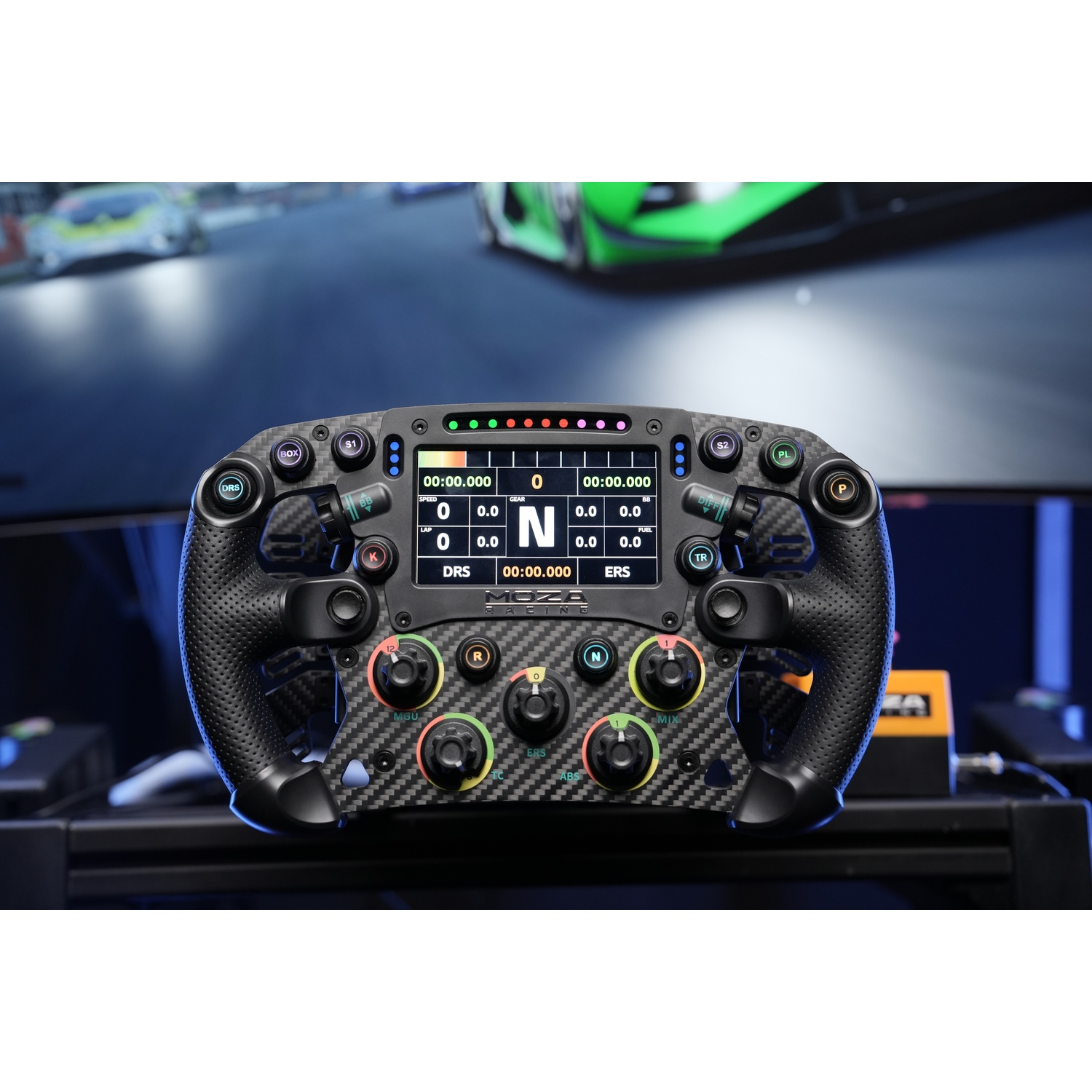 Un volante da corsa nero con display digitale e molti pulsanti davanti a una pista da corsa sfocata.