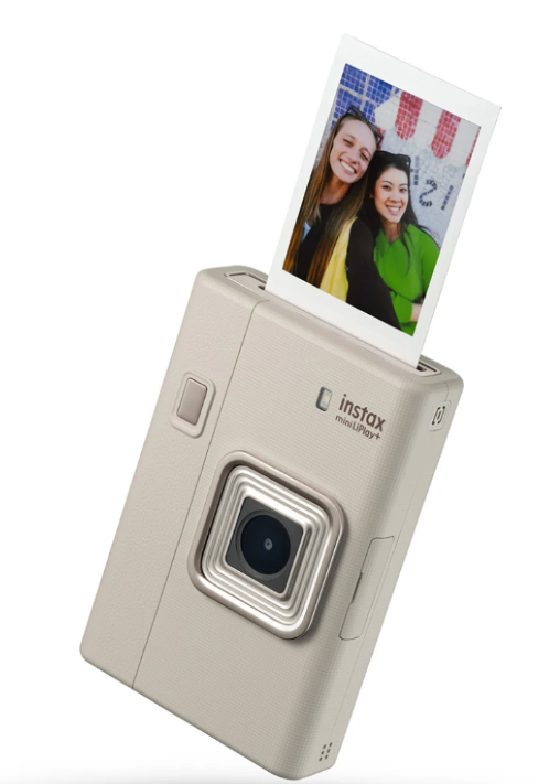 Beżowa drukarka Instax Mini LiPlay drukuje zdjęcie dwóch uśmiechniętych kobiet.