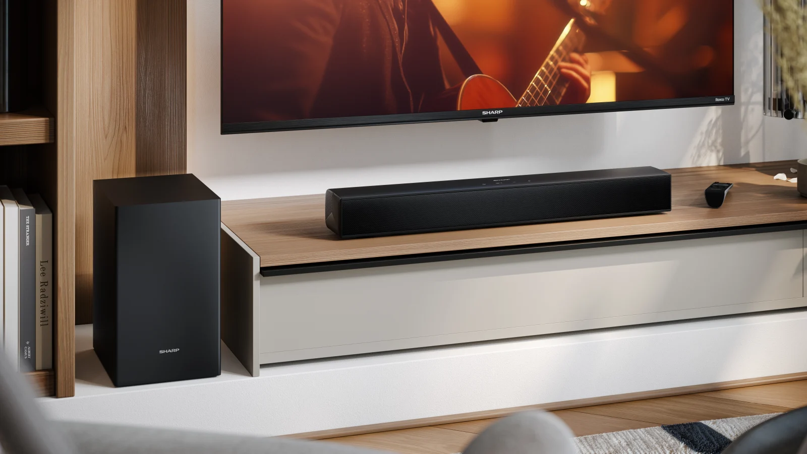 Un subwoofer y barra de sonido negros delante de un televisor con un guitarrista.