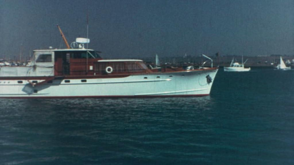Ein großes weißes und rotes Boot fährt auf dem Wasser, ein kleineres Boot im Hintergrund.
