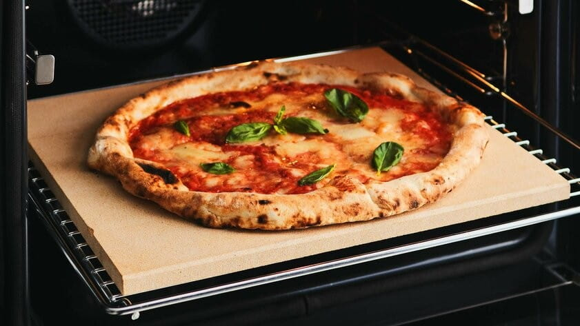 Pizza Margherita z bazylią piecze się na kamieniu w piekarniku.