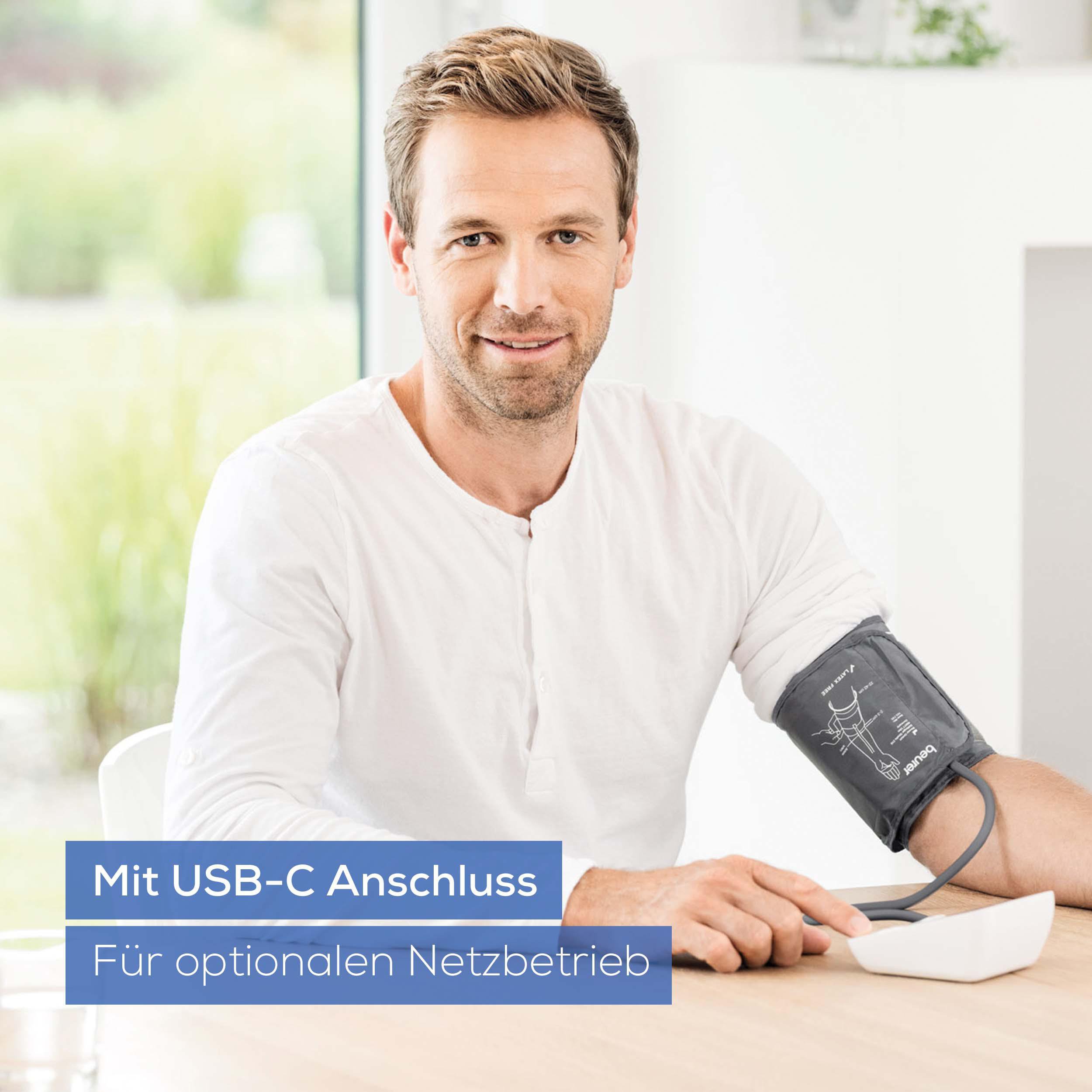 Mann mit Blutdruckmanschette am Arm, zeigt auf Gerät. Blaue Textfelder.