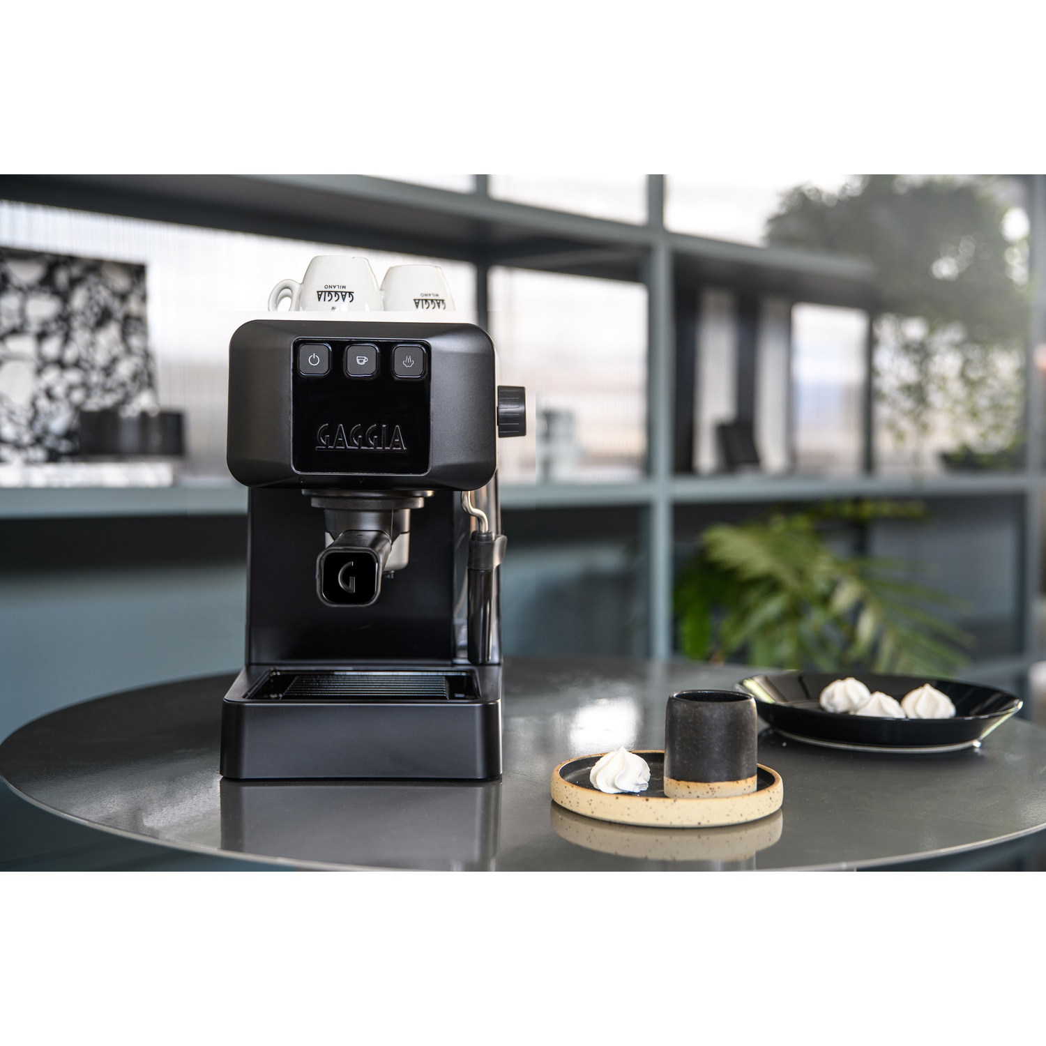 Macchina per espresso nera con due tazze, tazzina e meringhe.