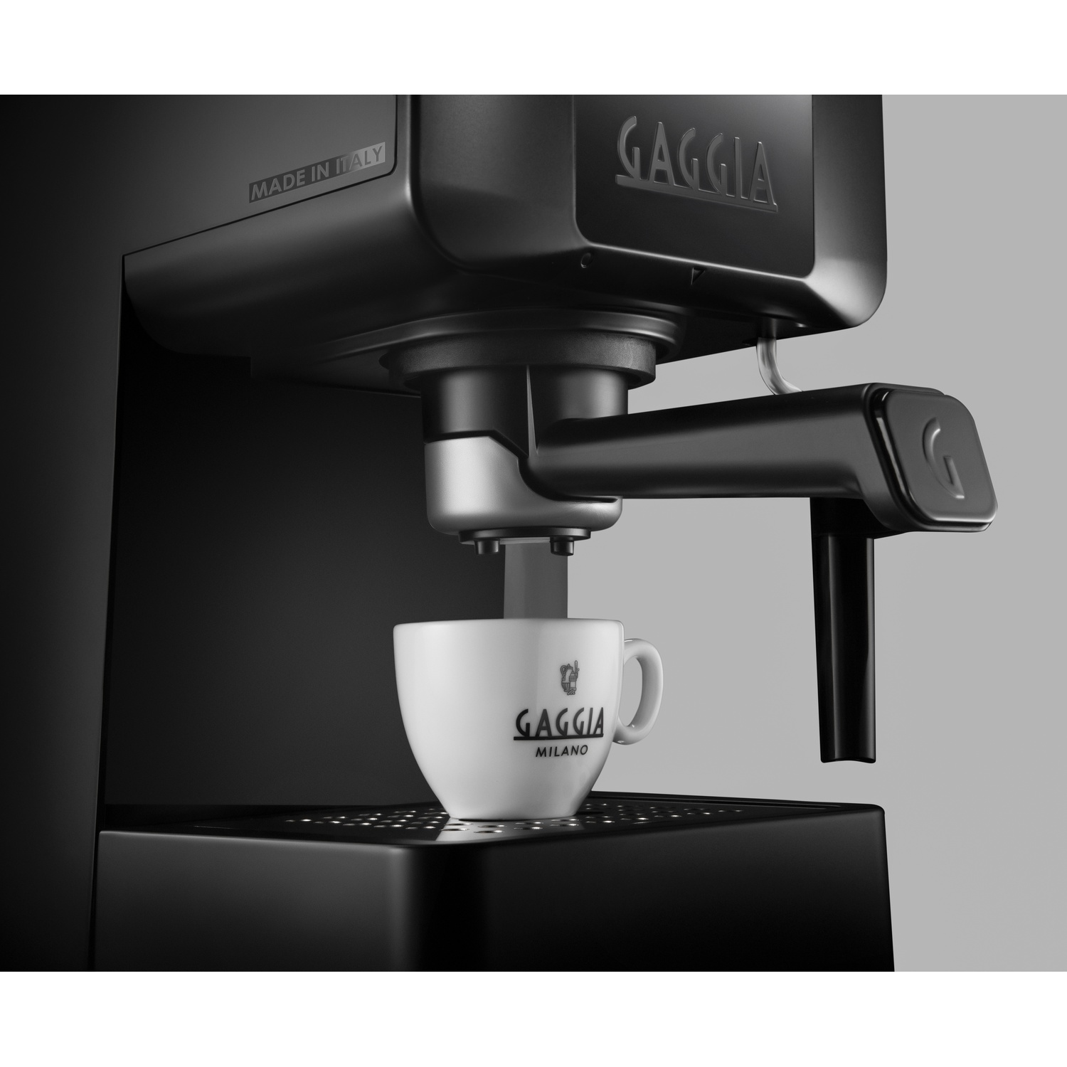 Una macchina per espresso nera prepara caffè in una tazza bianca con logo Gaggia.