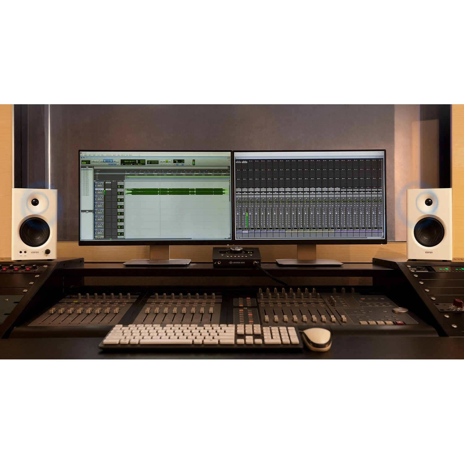 Due monitor da studio bianchi affiancano schermi di computer con software audio.
