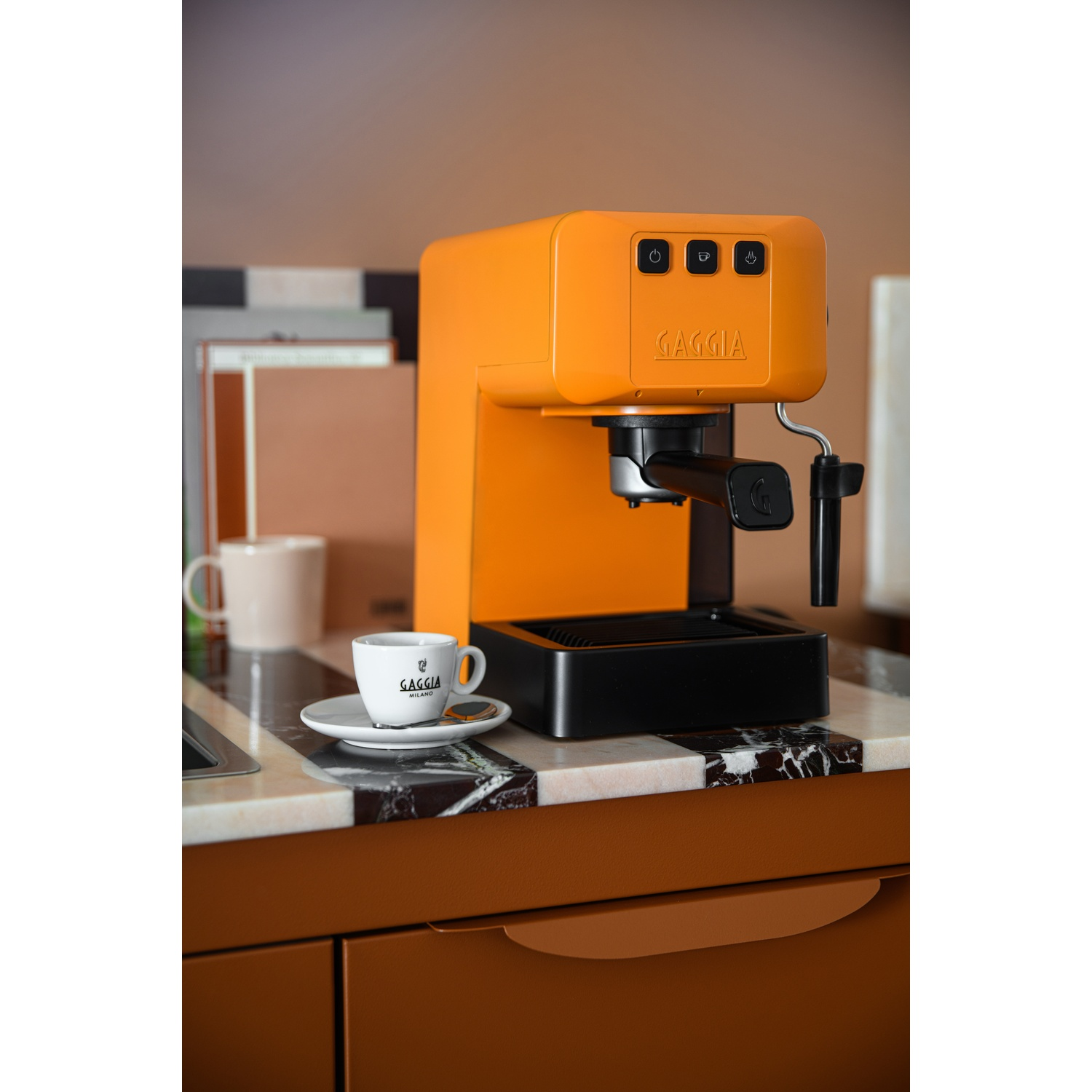 Macchina da caffè Gaggia arancione su bancone in marmo con tazza di caffè.
