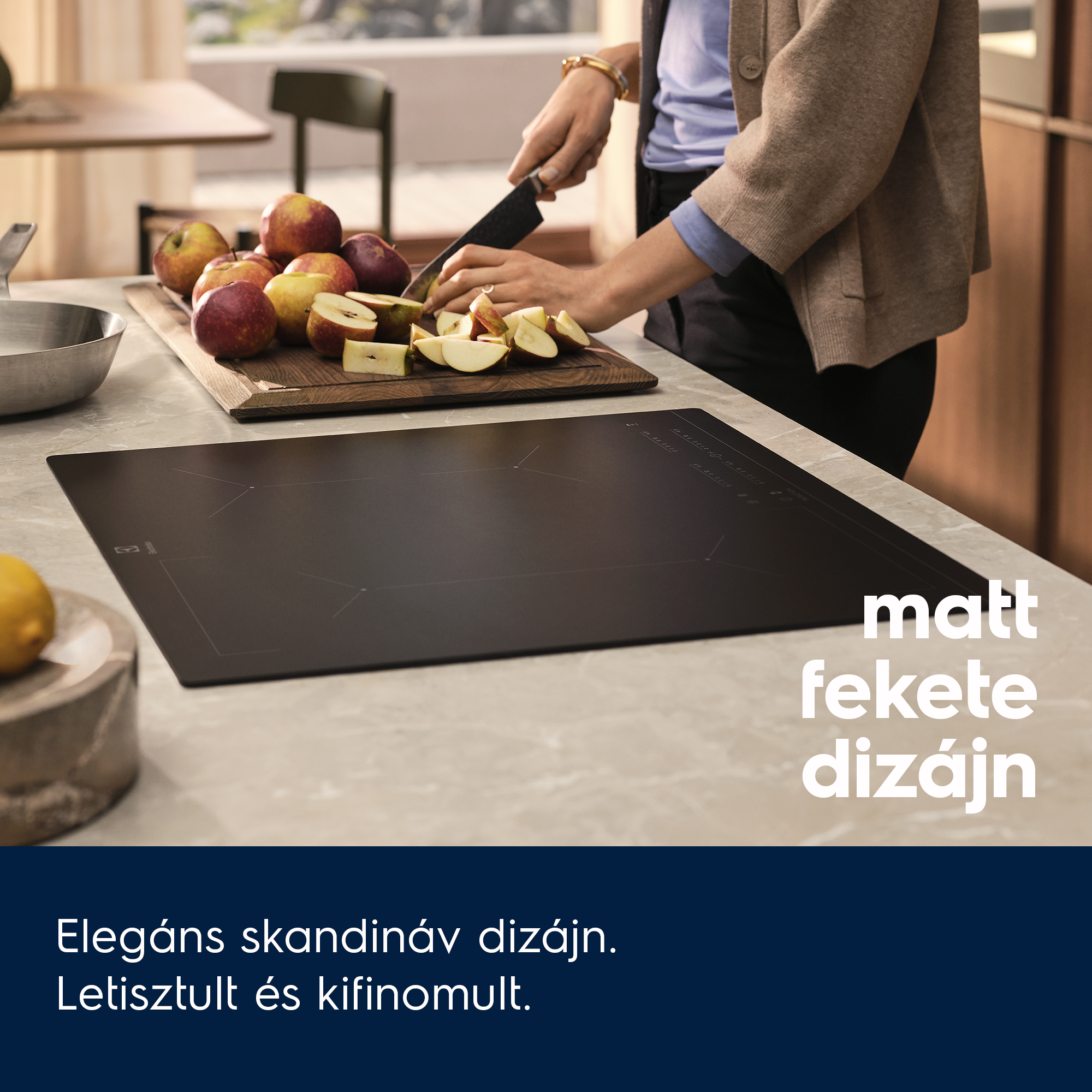 Egy személy almát vág egy fa deszkán. Indukciós főzőlap.