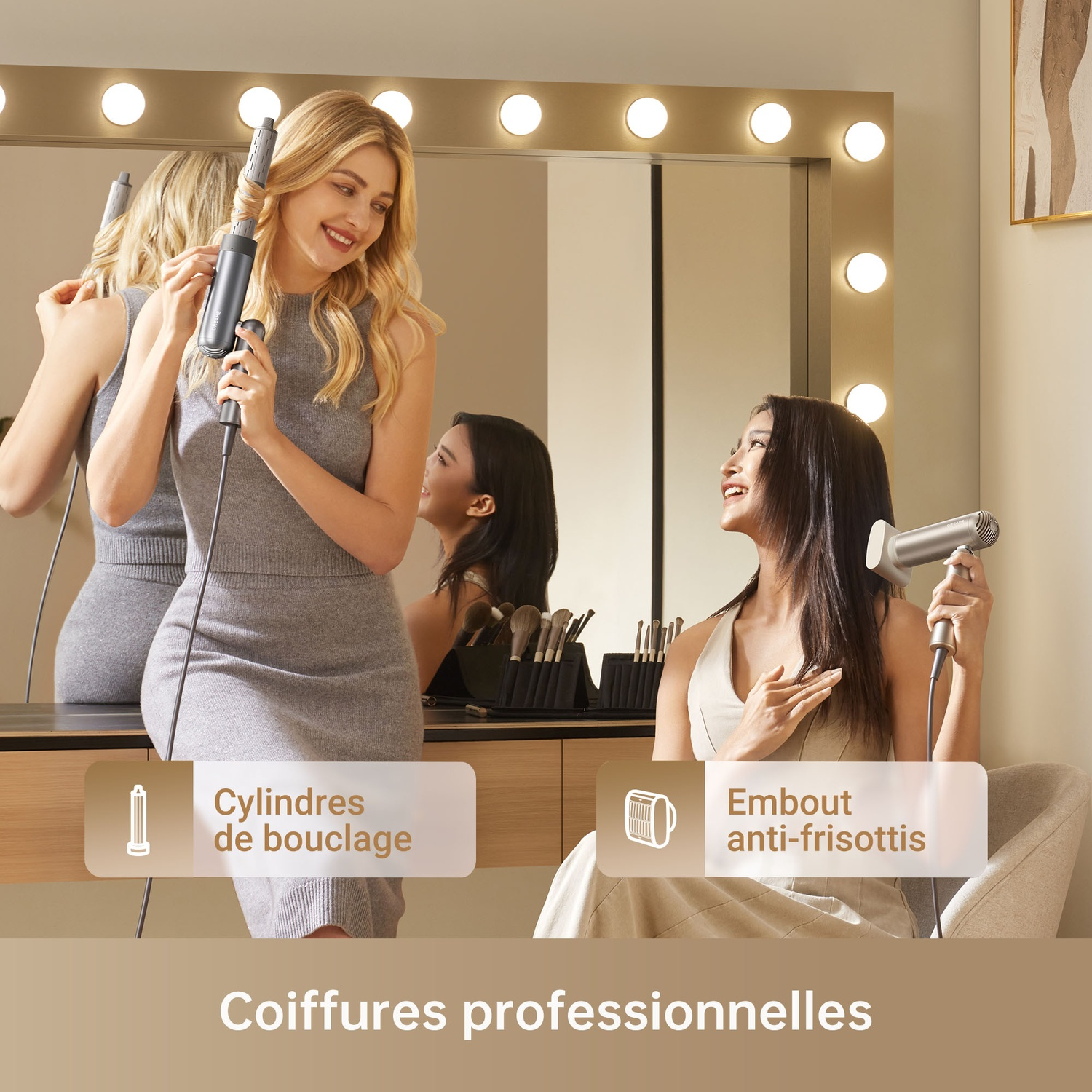 Two women styling hair in front of a mirror with lights. One curls, the other blow-dries.
