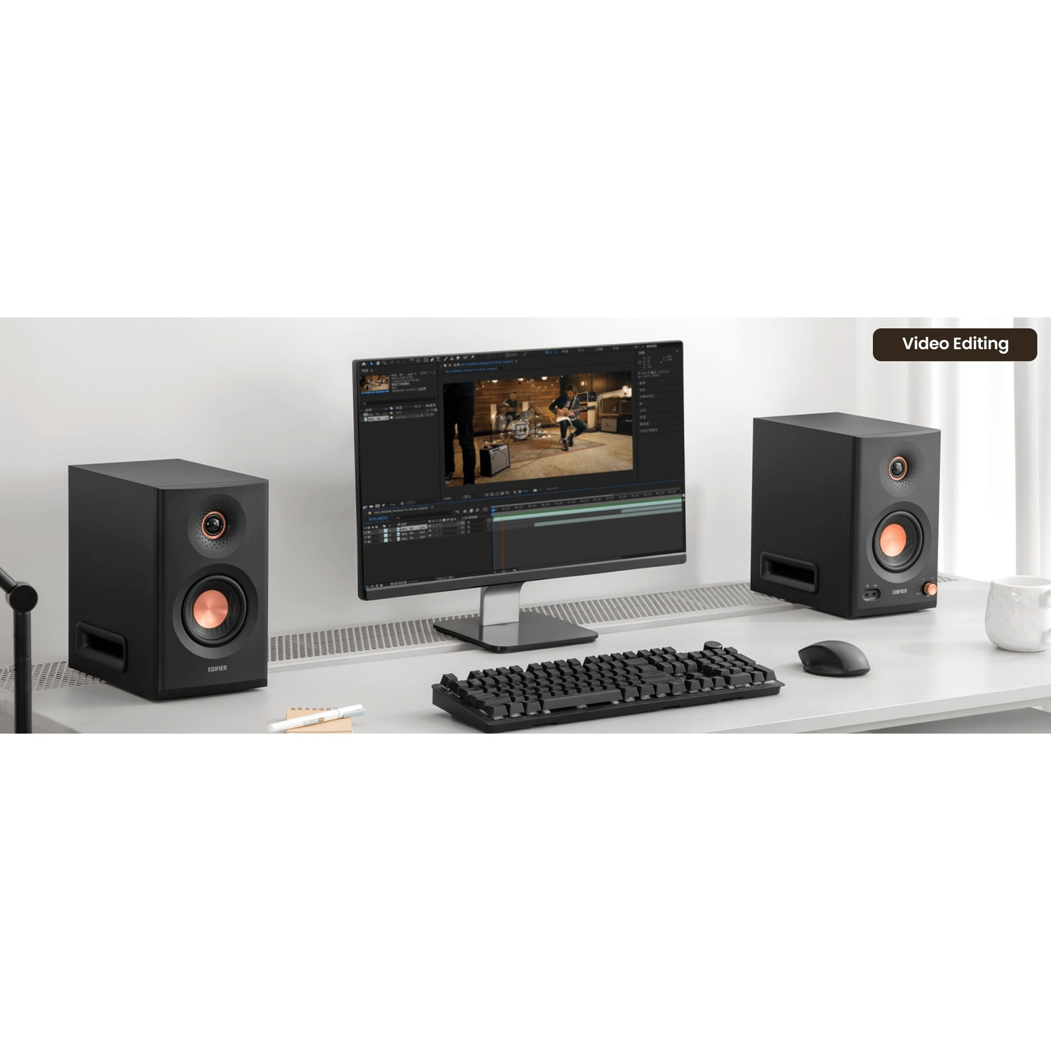 Una scrivania con due altoparlanti neri, monitor di editing video, tastiera e mouse.