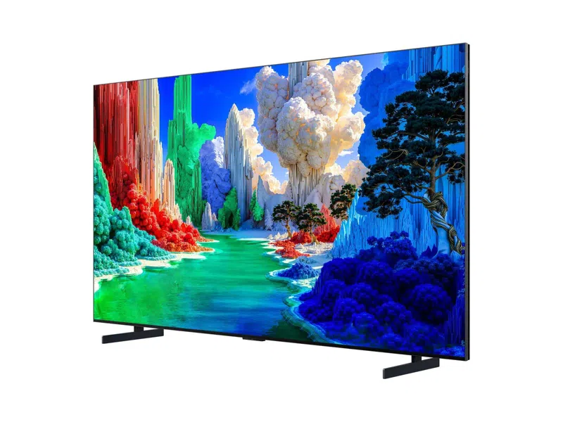 Egy modern síkképernyős TV szürrealista tájat mutat színes sziklákkal és türkizkék vízzel.