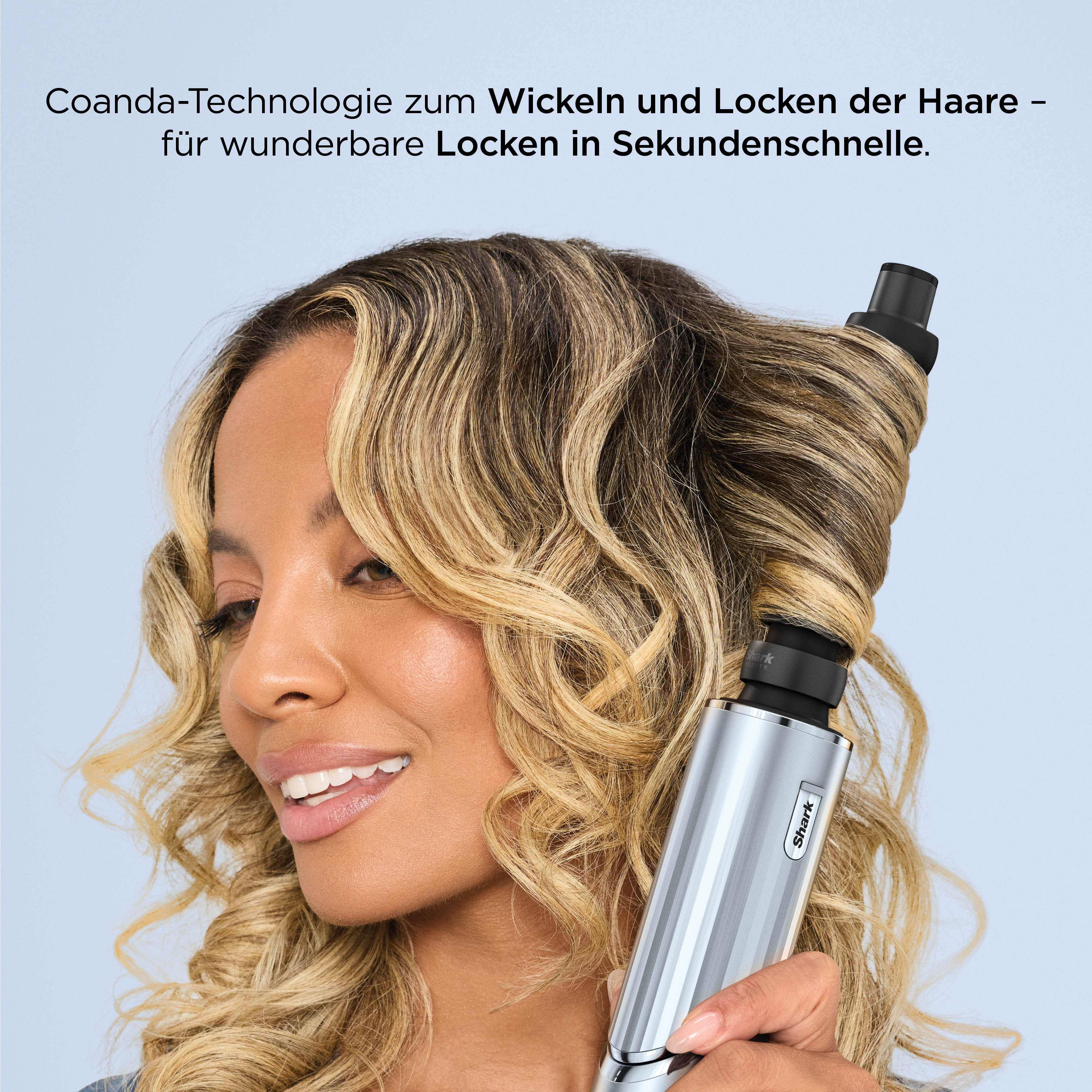 Eine Frau lockt ihr blondes Haar mit einem silbernen Shark-Haarstyler.