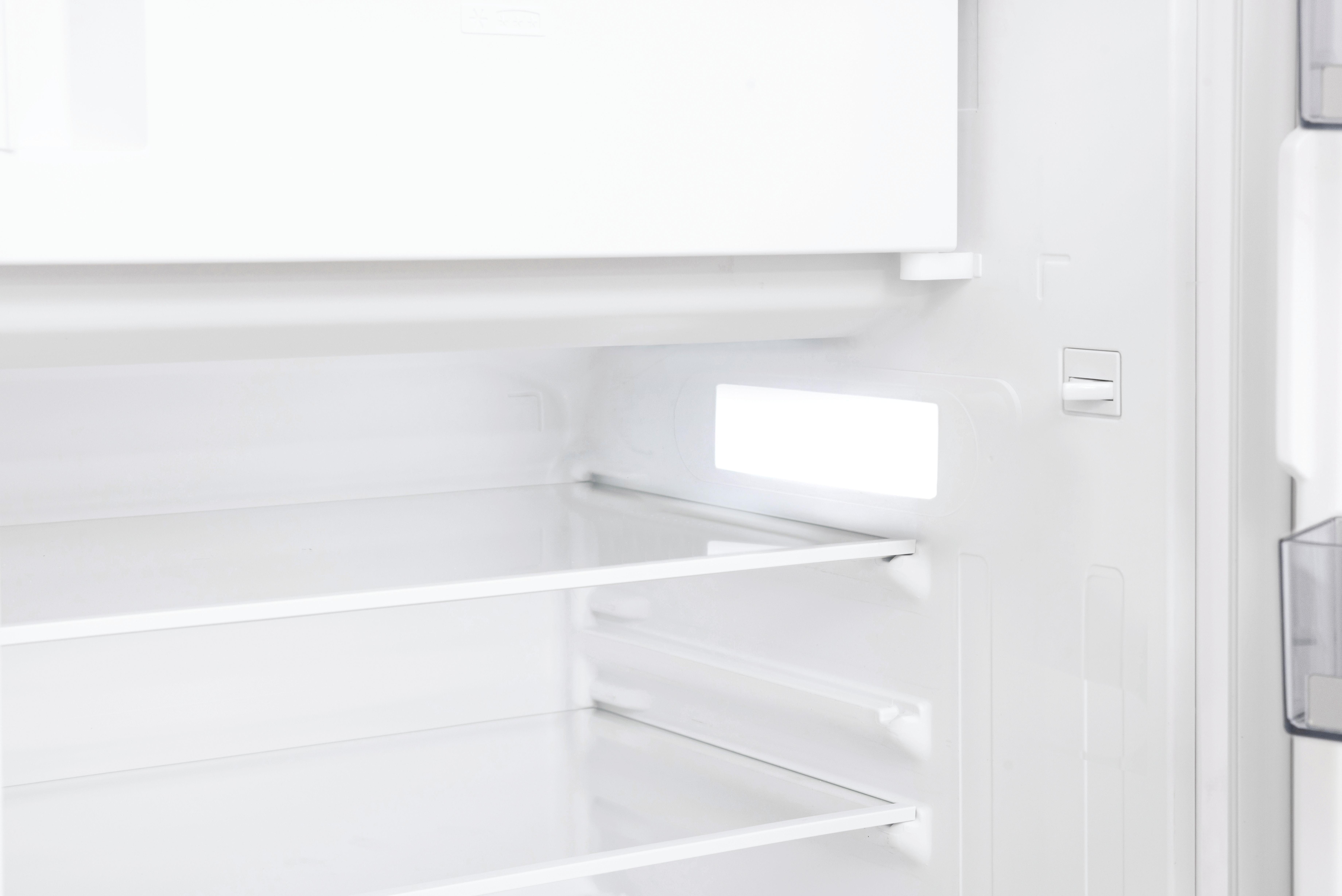 Leeres weißes Kühlschrankinterieur mit Regalen und Licht.