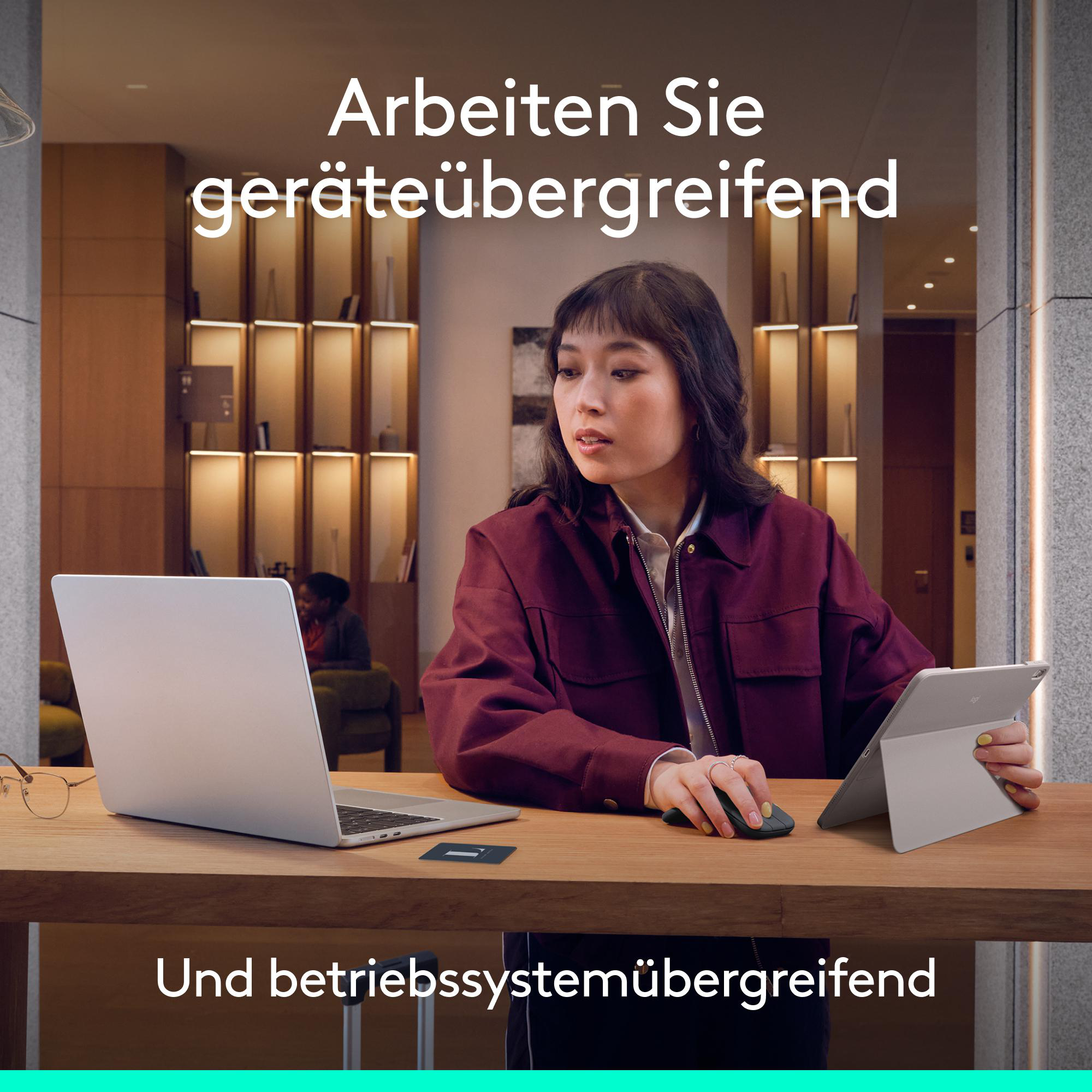 Eine Frau arbeitet an einem Laptop und Tablet in einem modernen Büro.