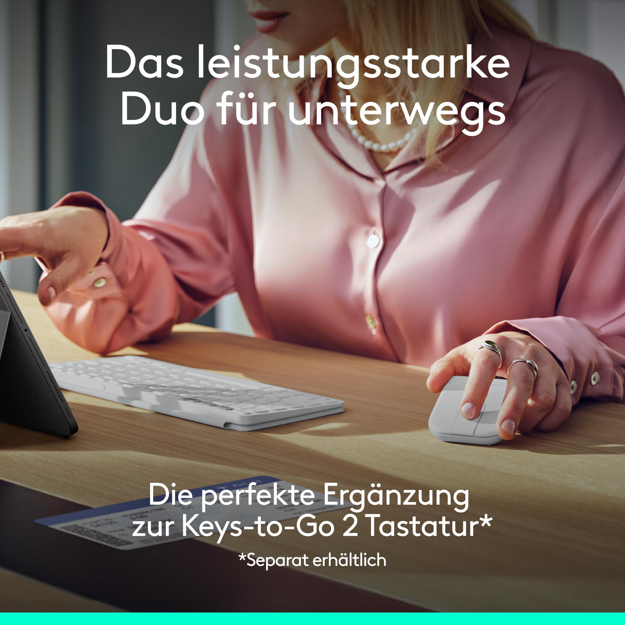 Eine Person mit Perlenkette und rosa Hemd benutzt eine weiße Tastatur und Maus.