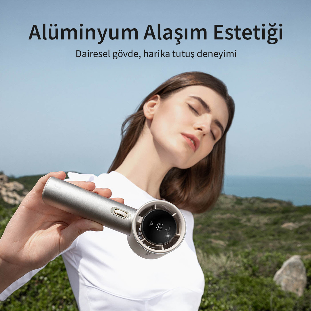 Kadın dışarıda dijital ekranlı gümüş rengi taşınabilir vantilatör tutuyor.