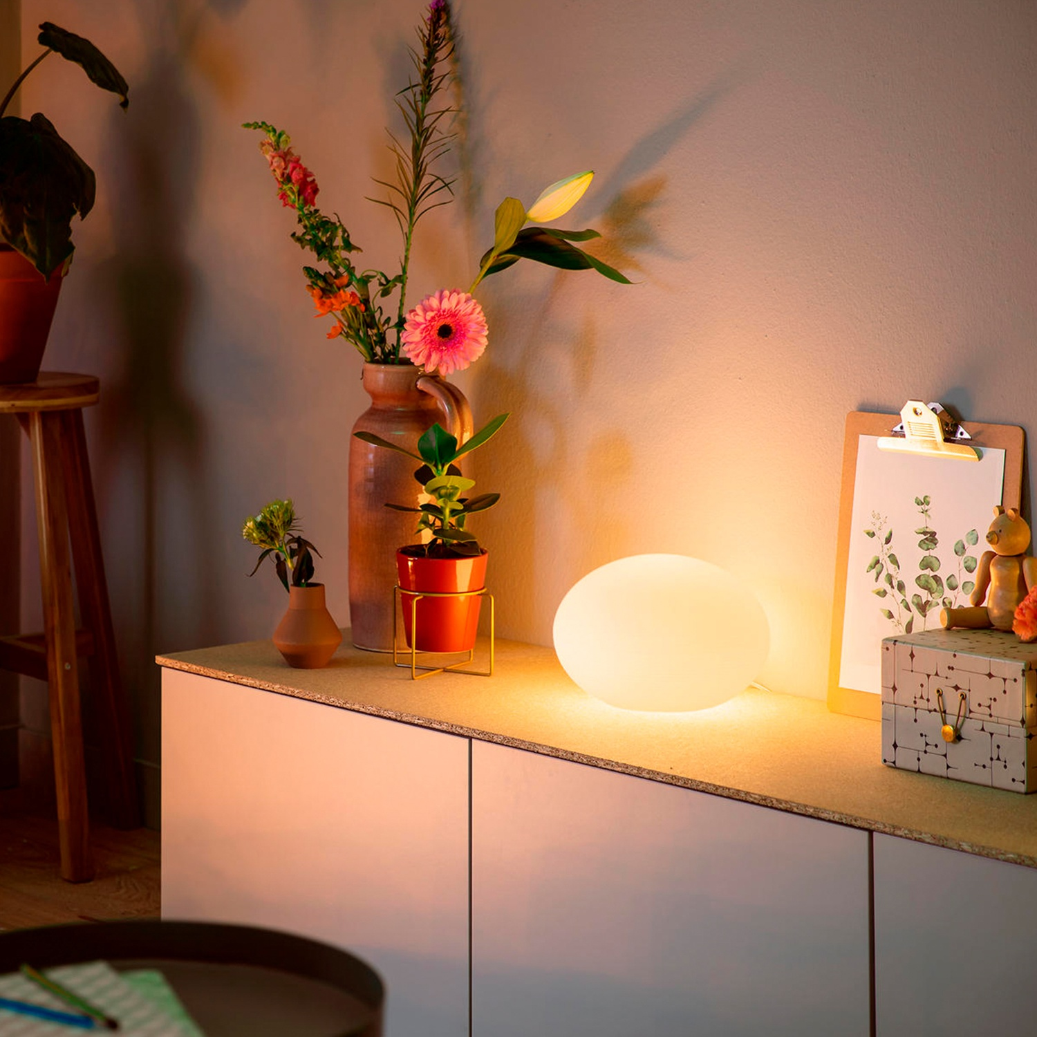 An oval, glowing bedside lamp globe on a sideboard.