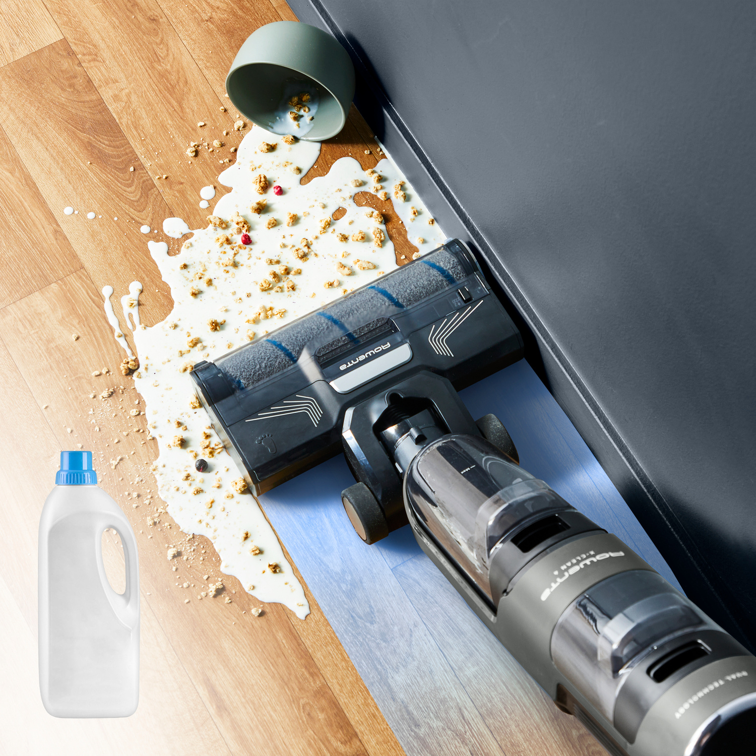 Un aspirapolvere pulisce cereali e latte versati su un pavimento in legno.