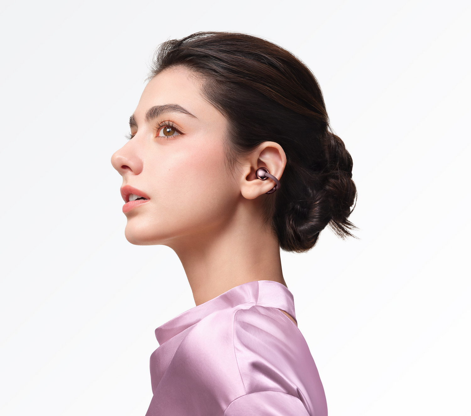 Vista de perfil de una mujer con un auricular y un top de seda púrpura.