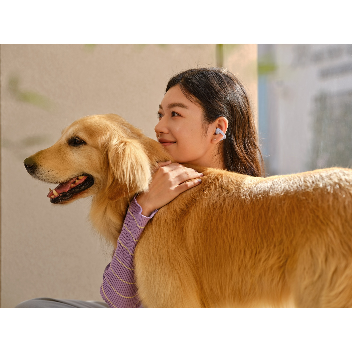 Een vrouw knuffelt een golden retriever, beiden dragen oordopjes.