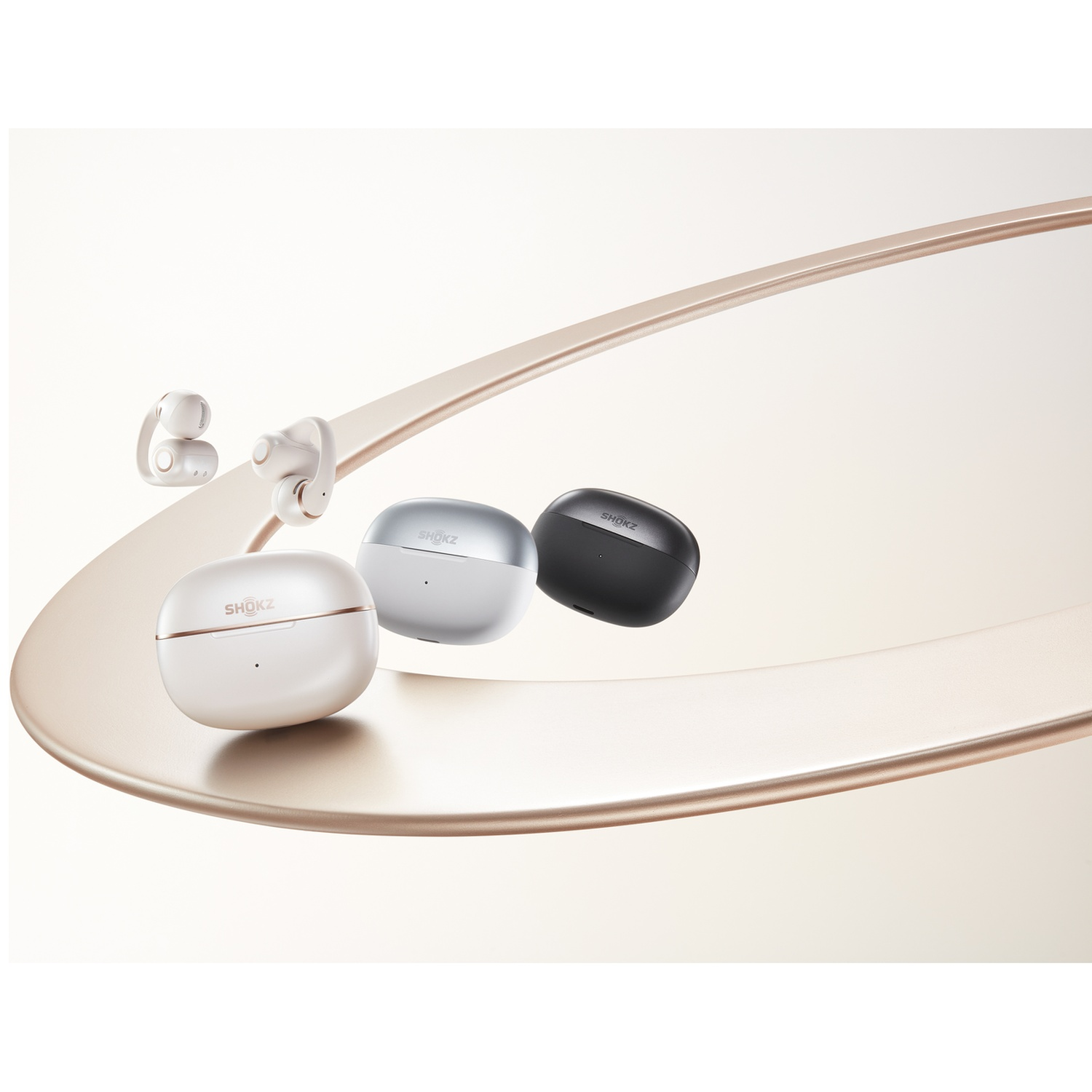 Drie Shokz oordopjes oplaadcases in wit, zilver en zwart op een lint.