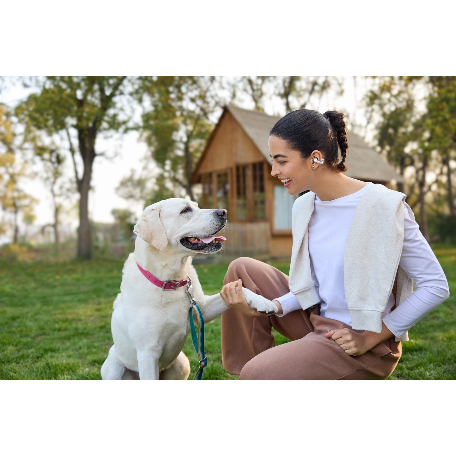 Een vrouw geeft een labrador buiten de poot.