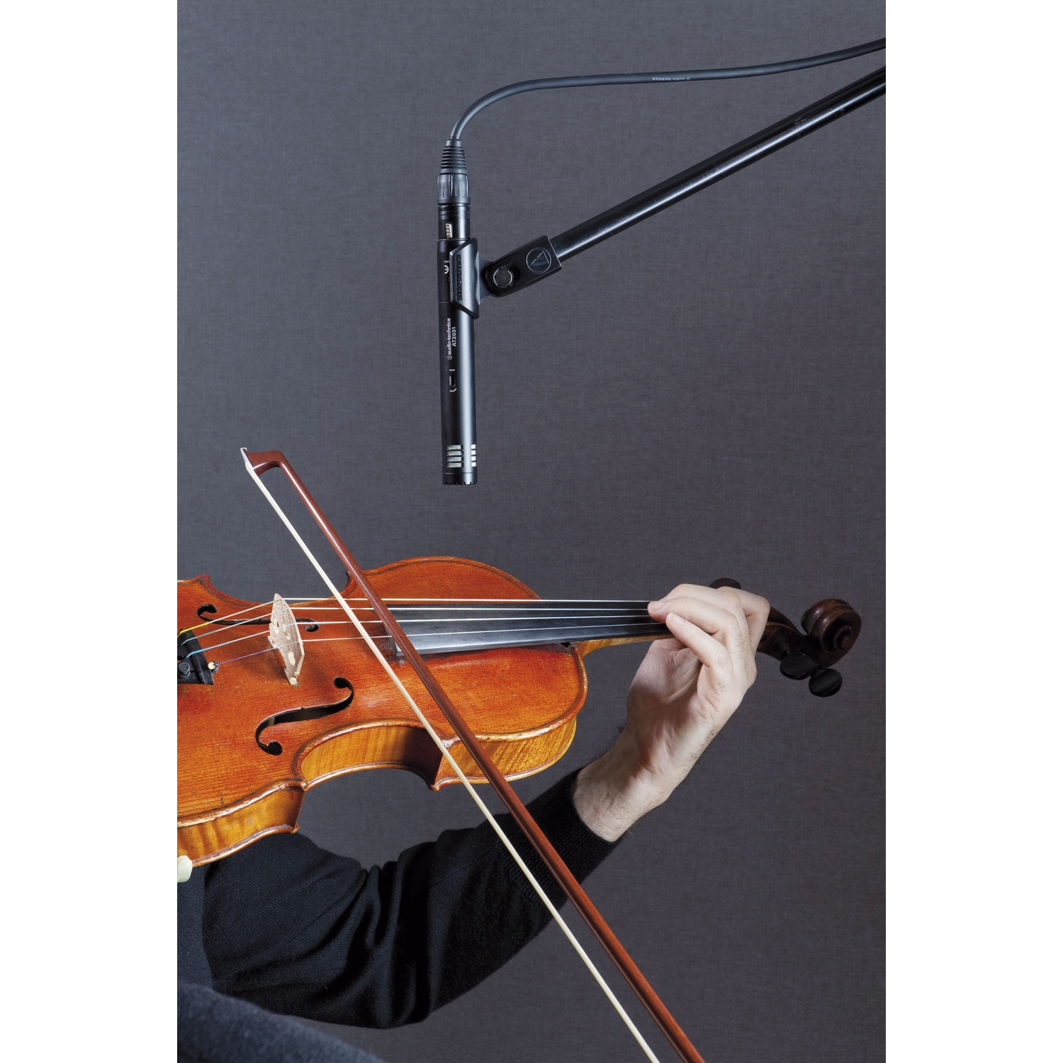 Una persona suona il violino, con un microfono su un braccio sopra.
