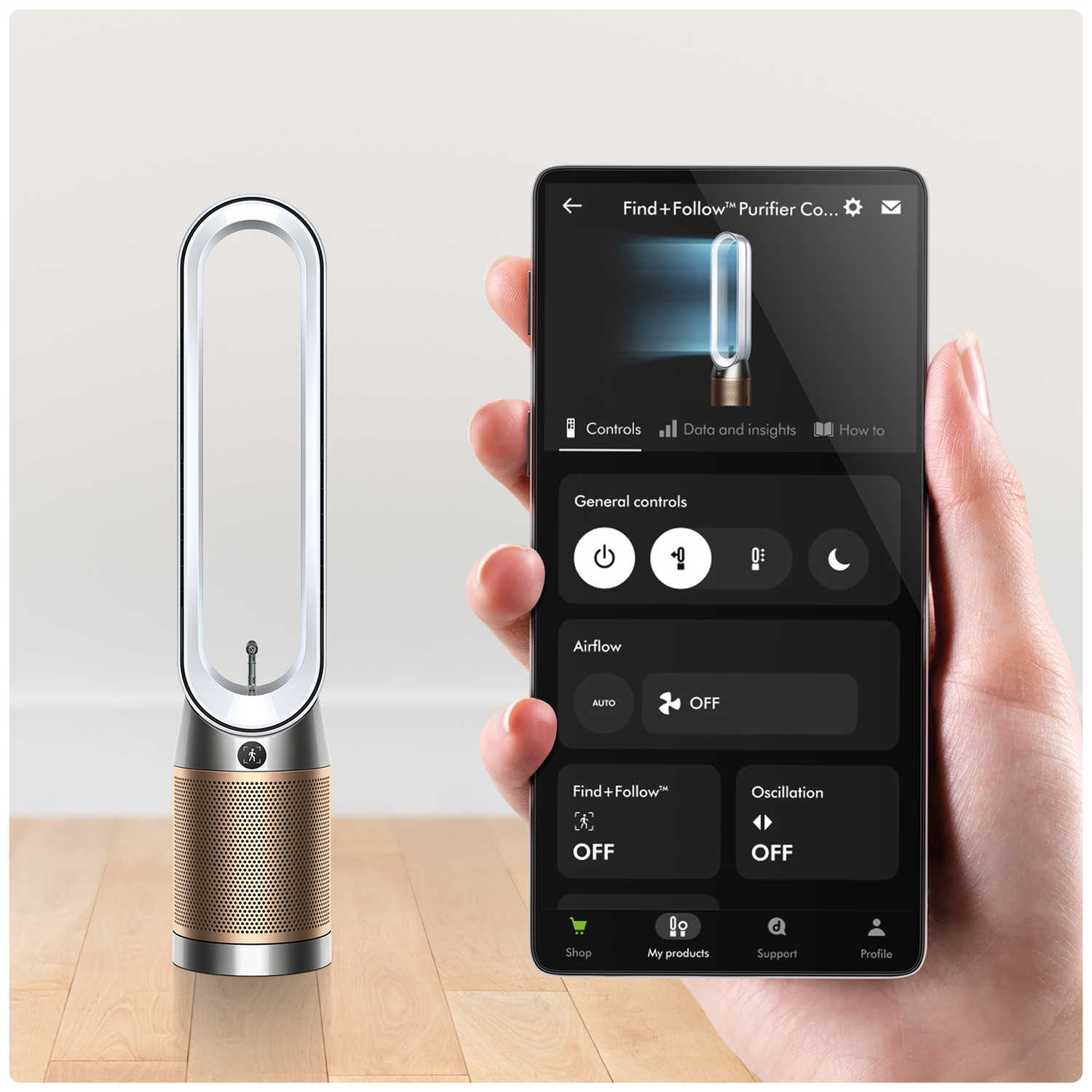 A Dyson air purifier with a silver ring and gold grille next to a smartphone.