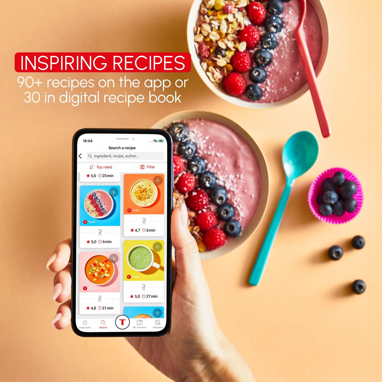 Mano che tiene un telefono con ricette accanto a due ciotole di bacche e muesli.
