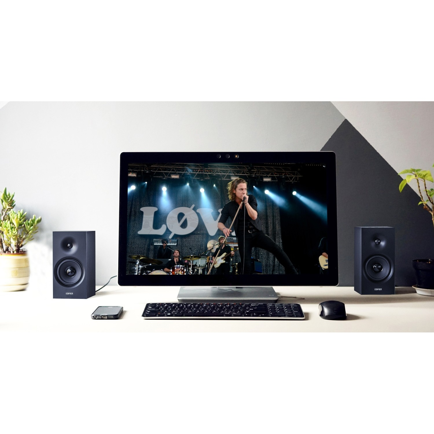 Un monitor mostra una band sul palco. Vicino ci sono altoparlanti, tastiera, mouse e telefono.
