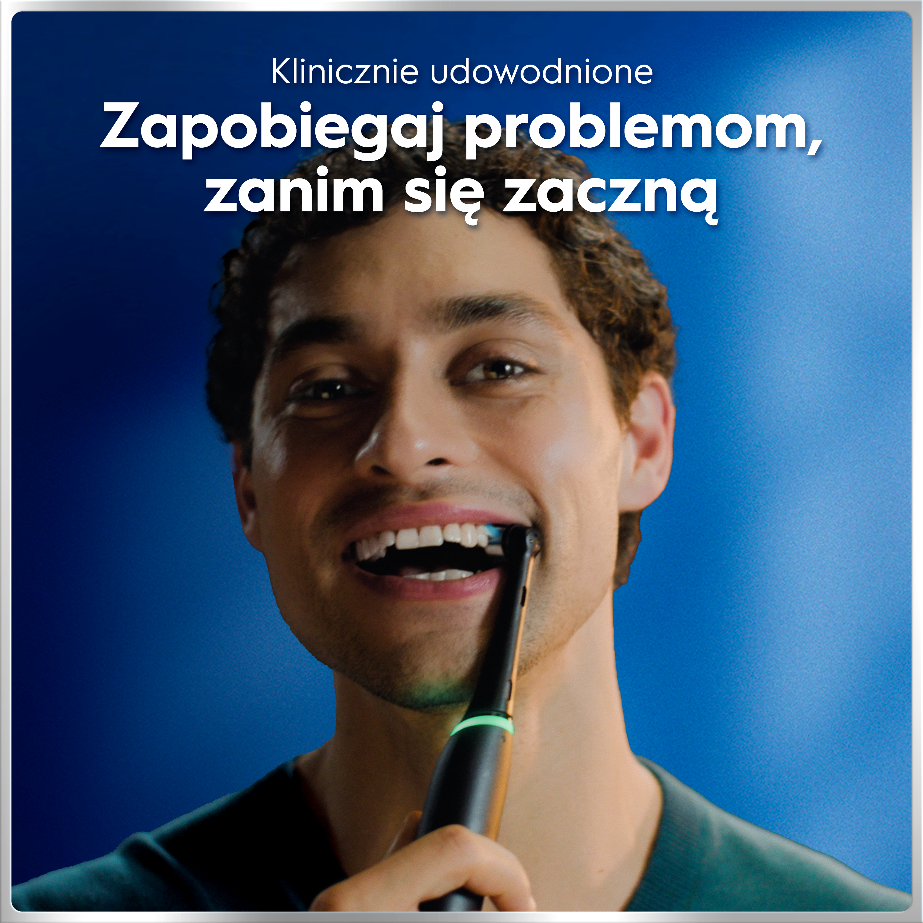 Mężczyzna myje zęby szczoteczką elektryczną na niebieskim tle.