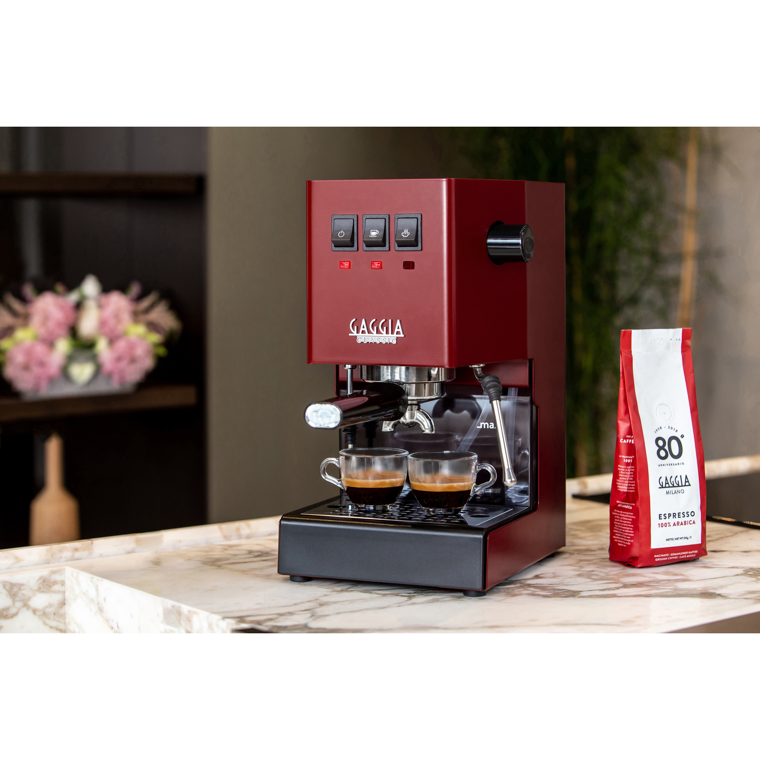 Una macchina per espresso Gaggia rossa con due tazze di espresso e un sacchetto di caffè.