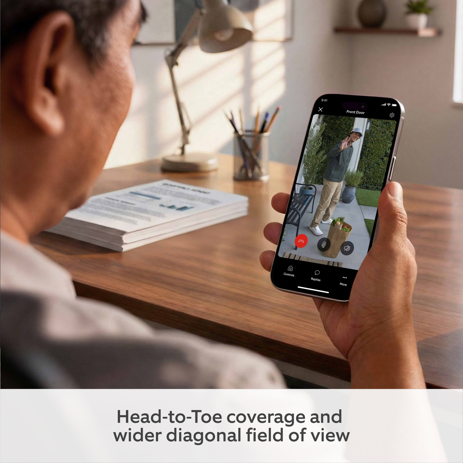 Man holds phone showing video of person at front door with groceries.