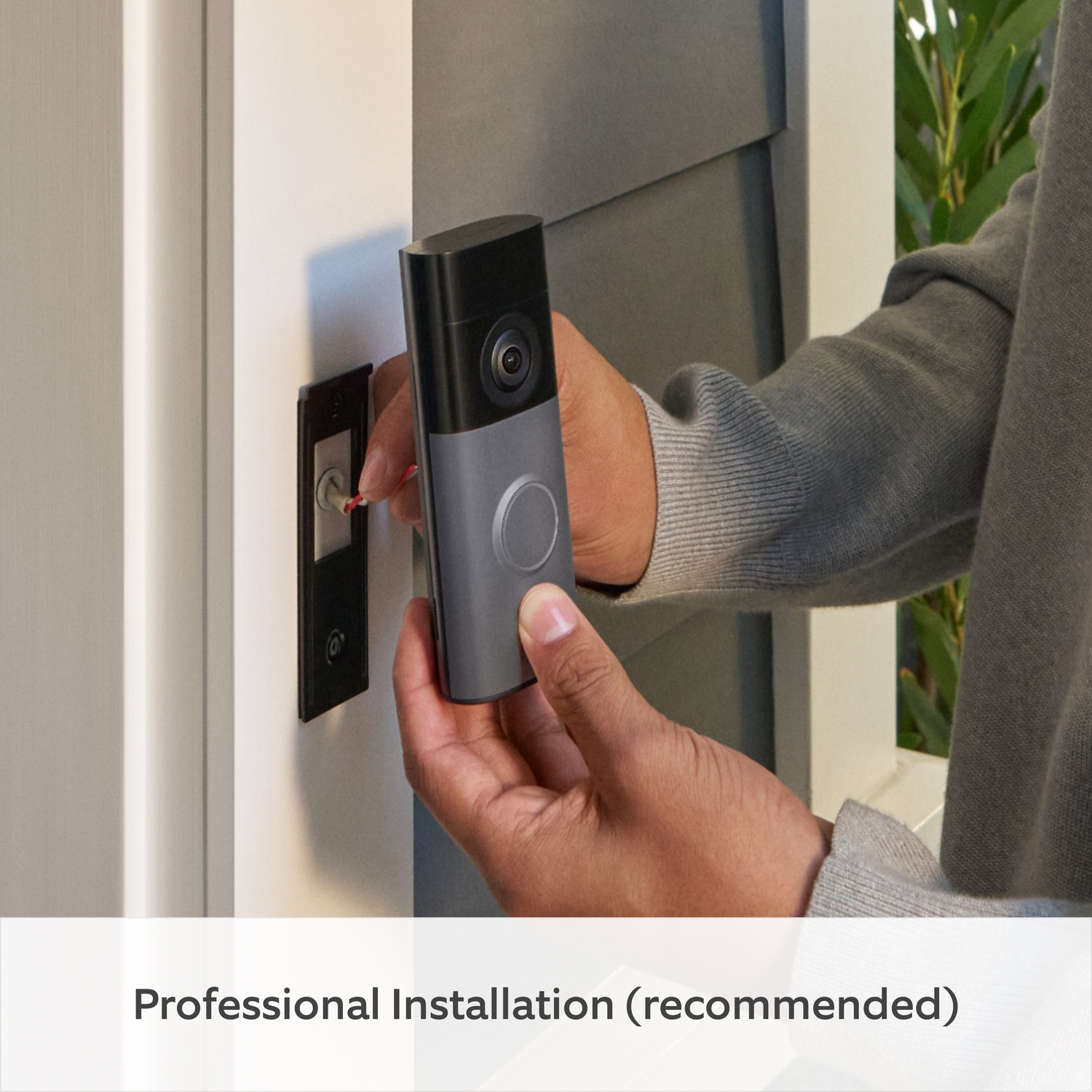 Hands installing a smart doorbell next to a white doorframe.