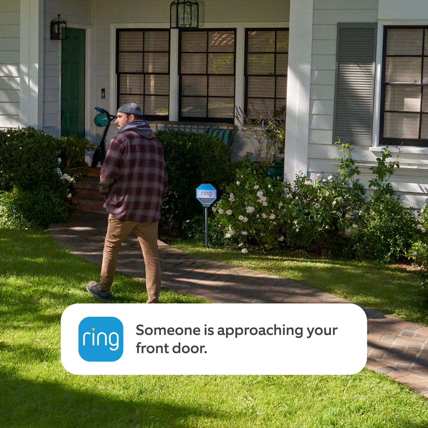 Man approaches house with bike; Ring sign in grass.