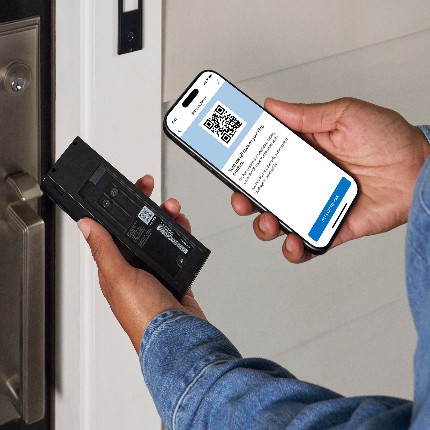 Une personne tient un smartphone affichant un code QR et un appareil Ring à proximité.
